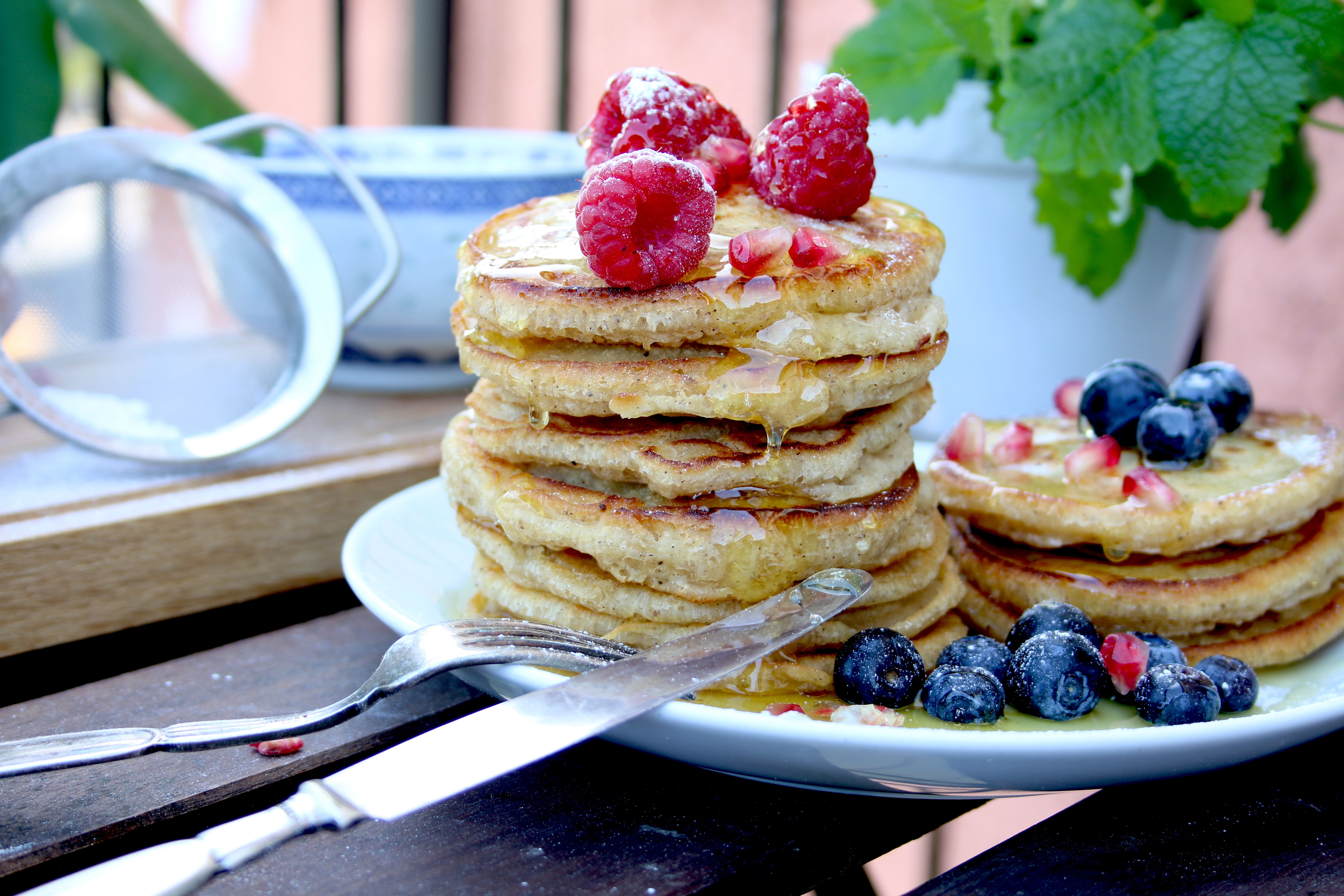 Veganska amerikanska pannkakor på en vit tallrik toppade med färska blåbär och hallon.