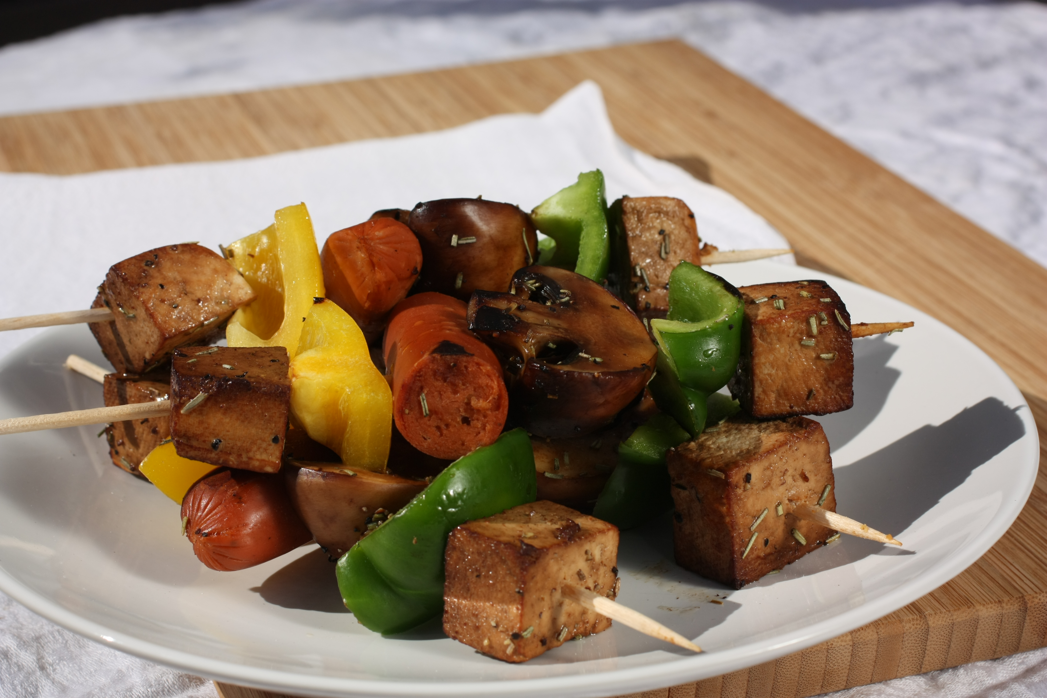 Grillspett med svamp, paprika, tofu och kryddig korv på en vit tallrik
