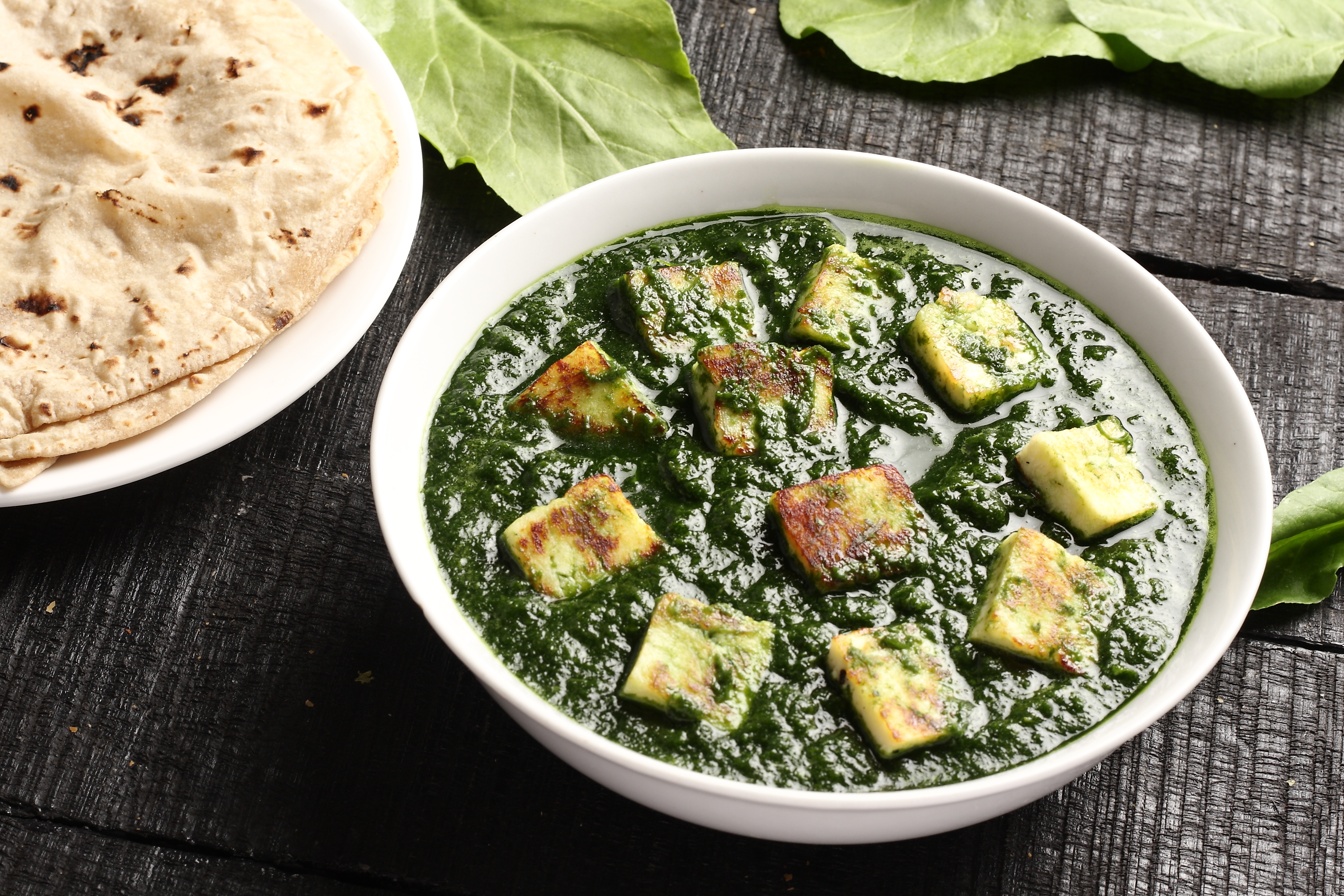 Palak paneer och naan bröd på ett mörkt bord