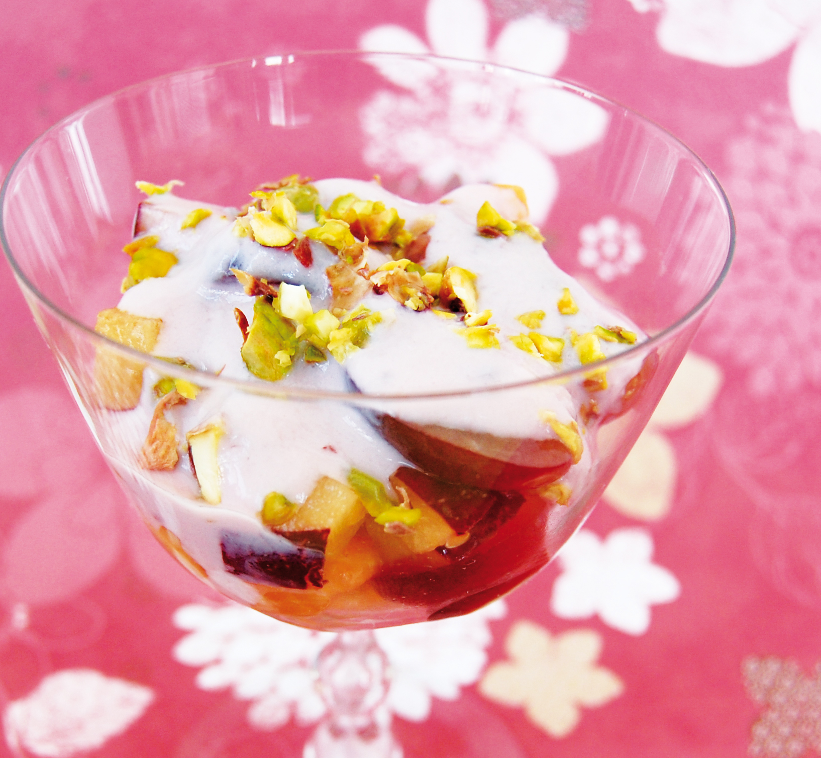 Fruktsallad med pistagenötter och vaniljyoghurt i en glasbägare.