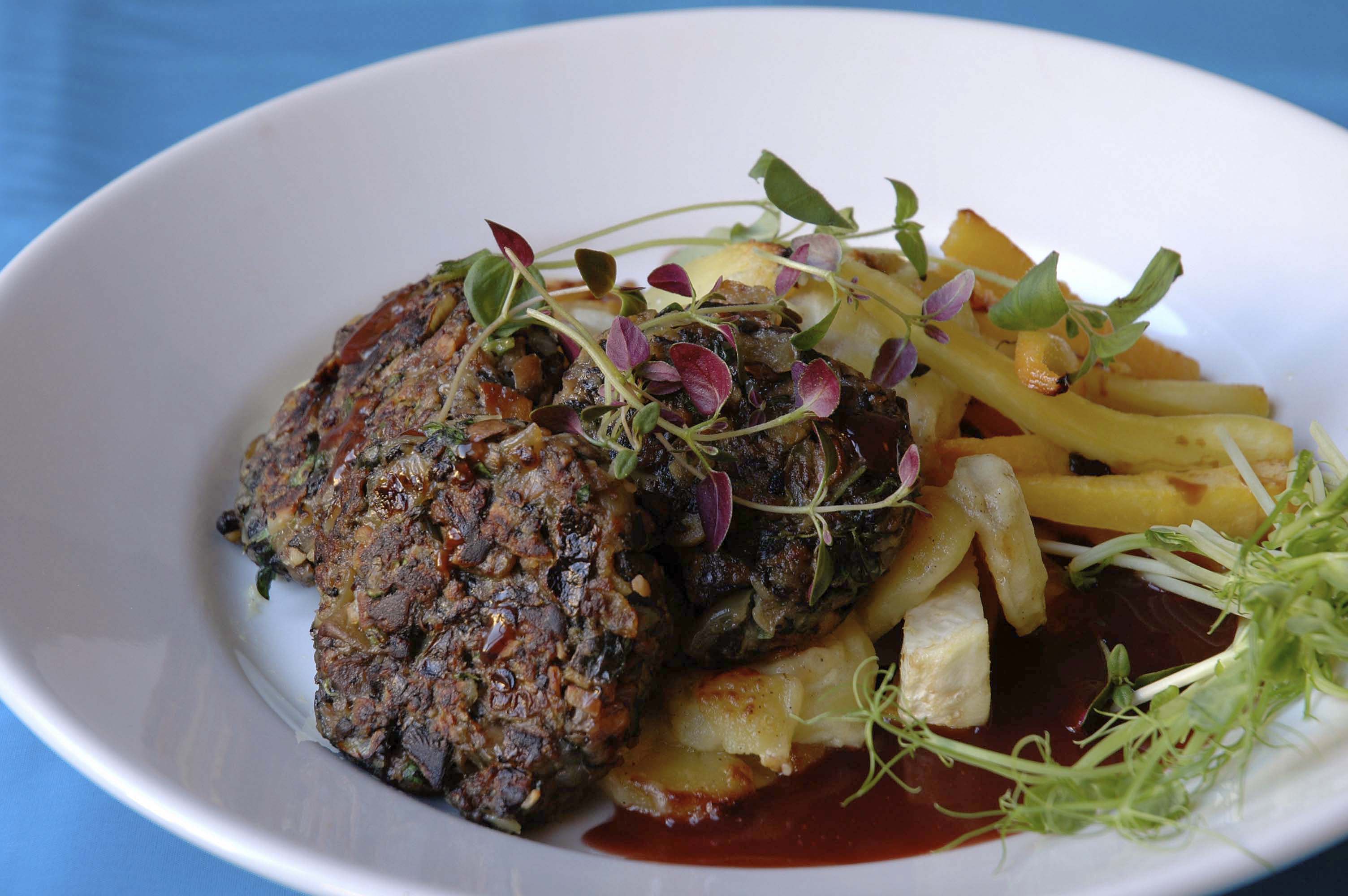 Veganska svampbiffar med sås och potatis på en vit tallrik.