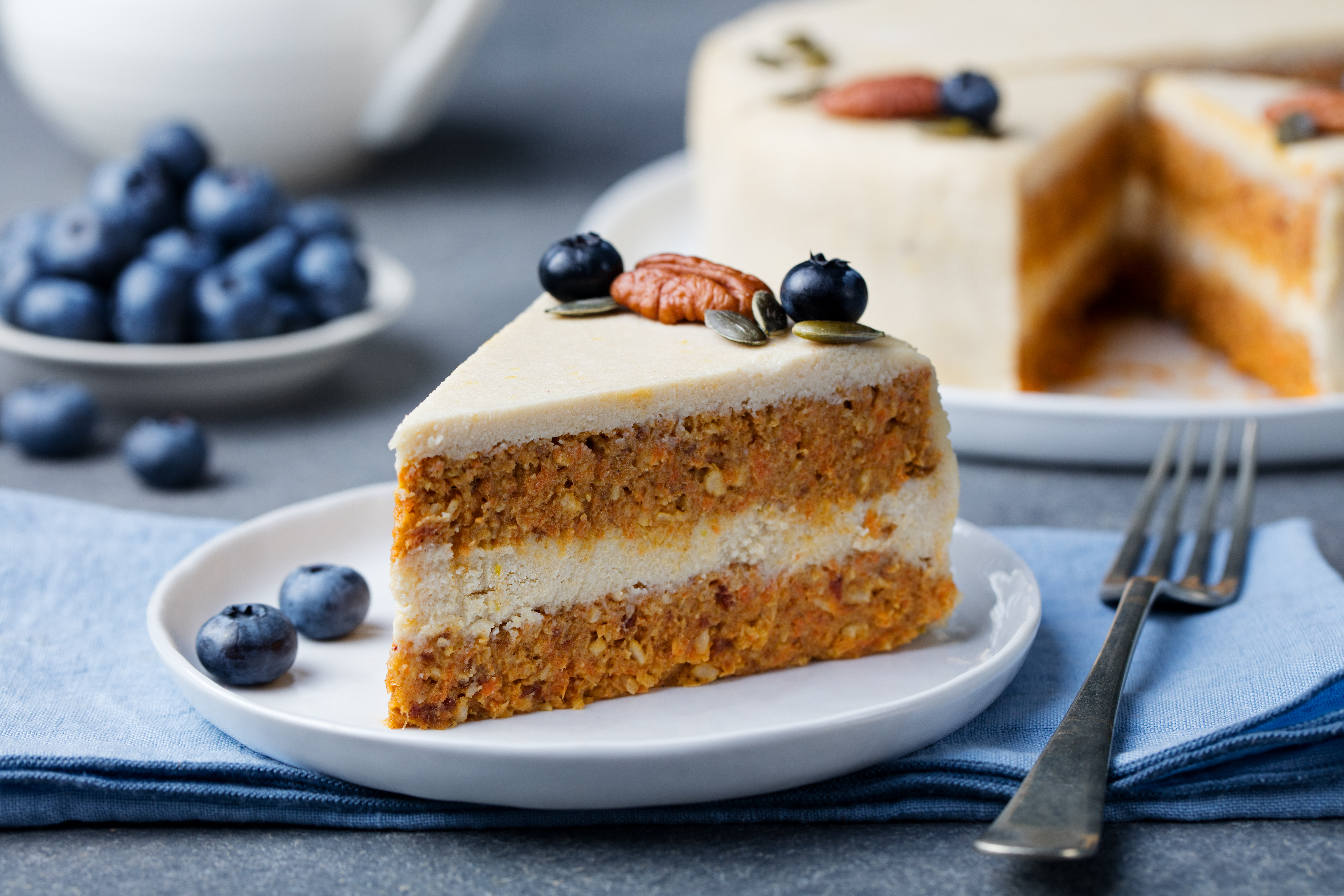 Vegansk morotskaka på en vit tallrik, bredvid tallrik ligger några blåbär