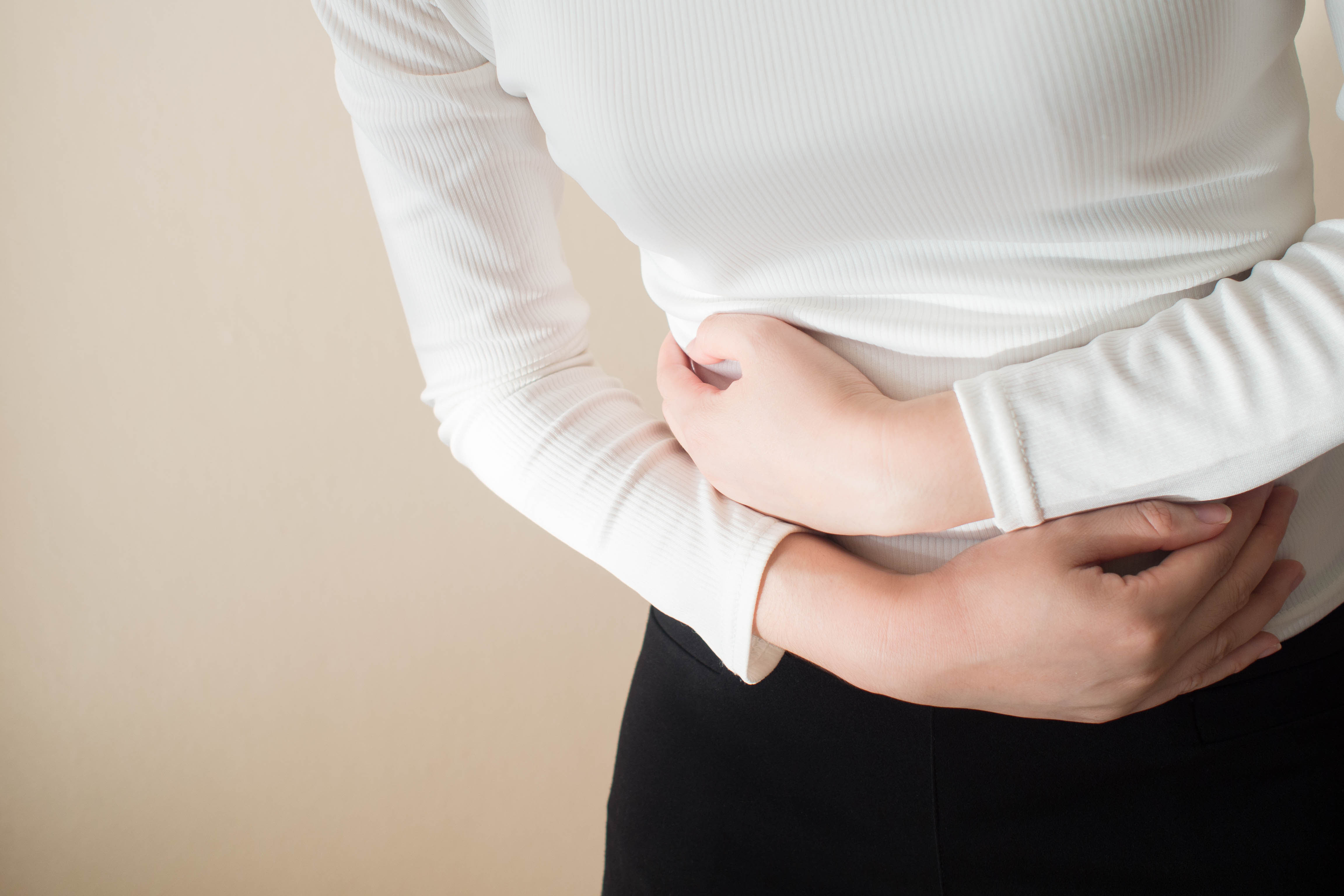 Young female suffering form stomach ache on gray background