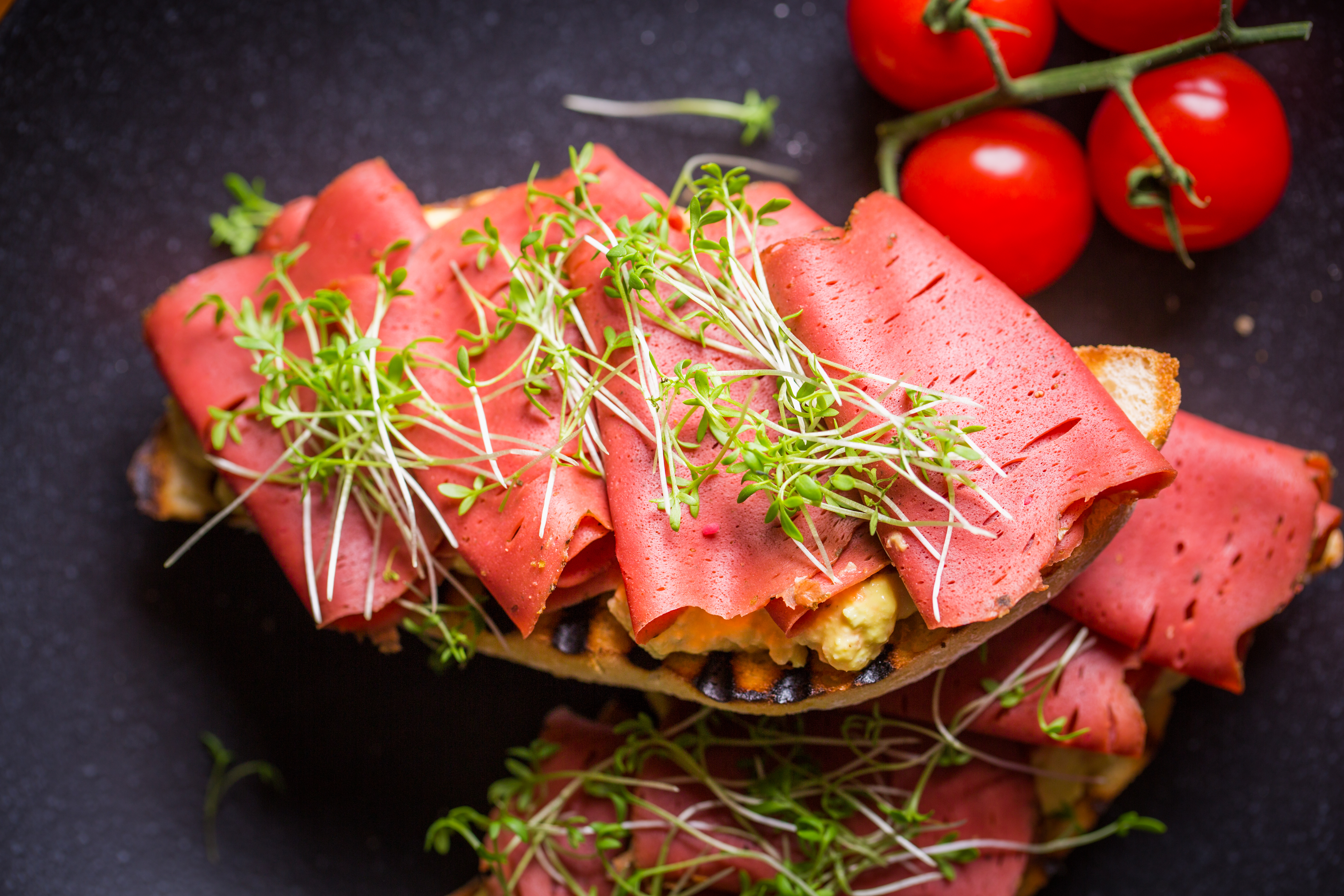 Vegansk skinka på en macka toppad med en gröna blad