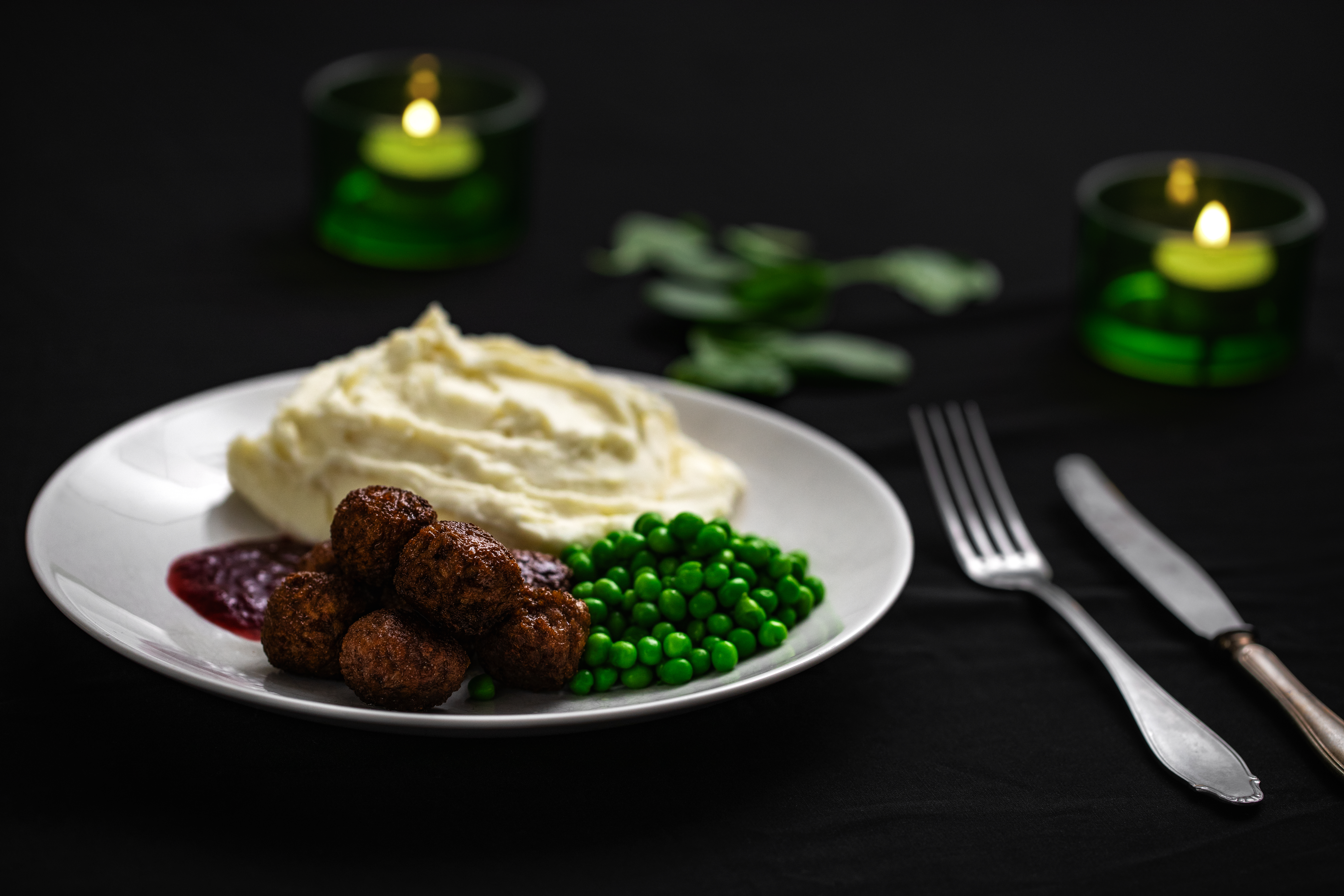 veganska köttbullar, potatismos och gröna ärtor på en vit tallrik