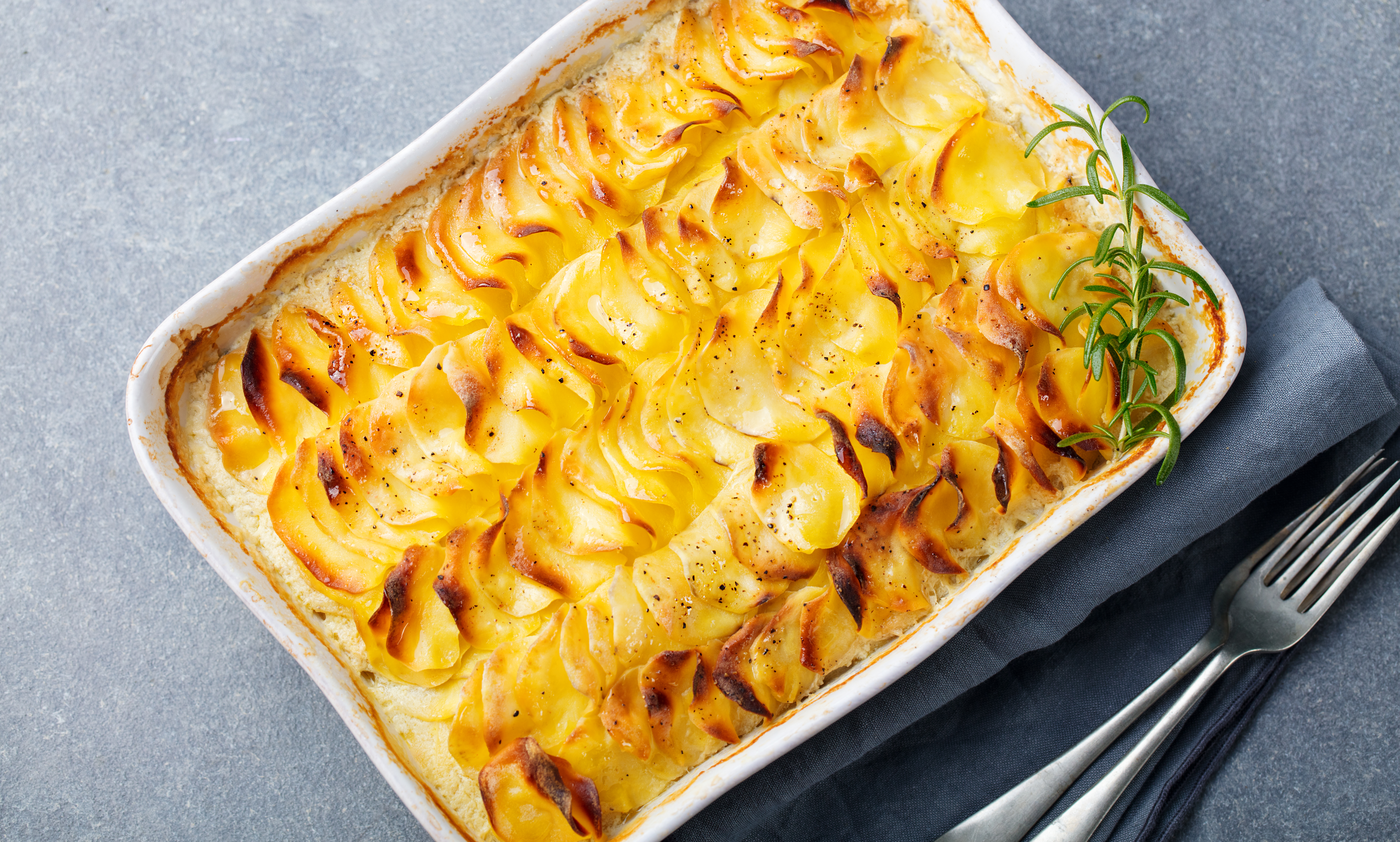 Potatisgratäng i en ugnsform på ett grått bord