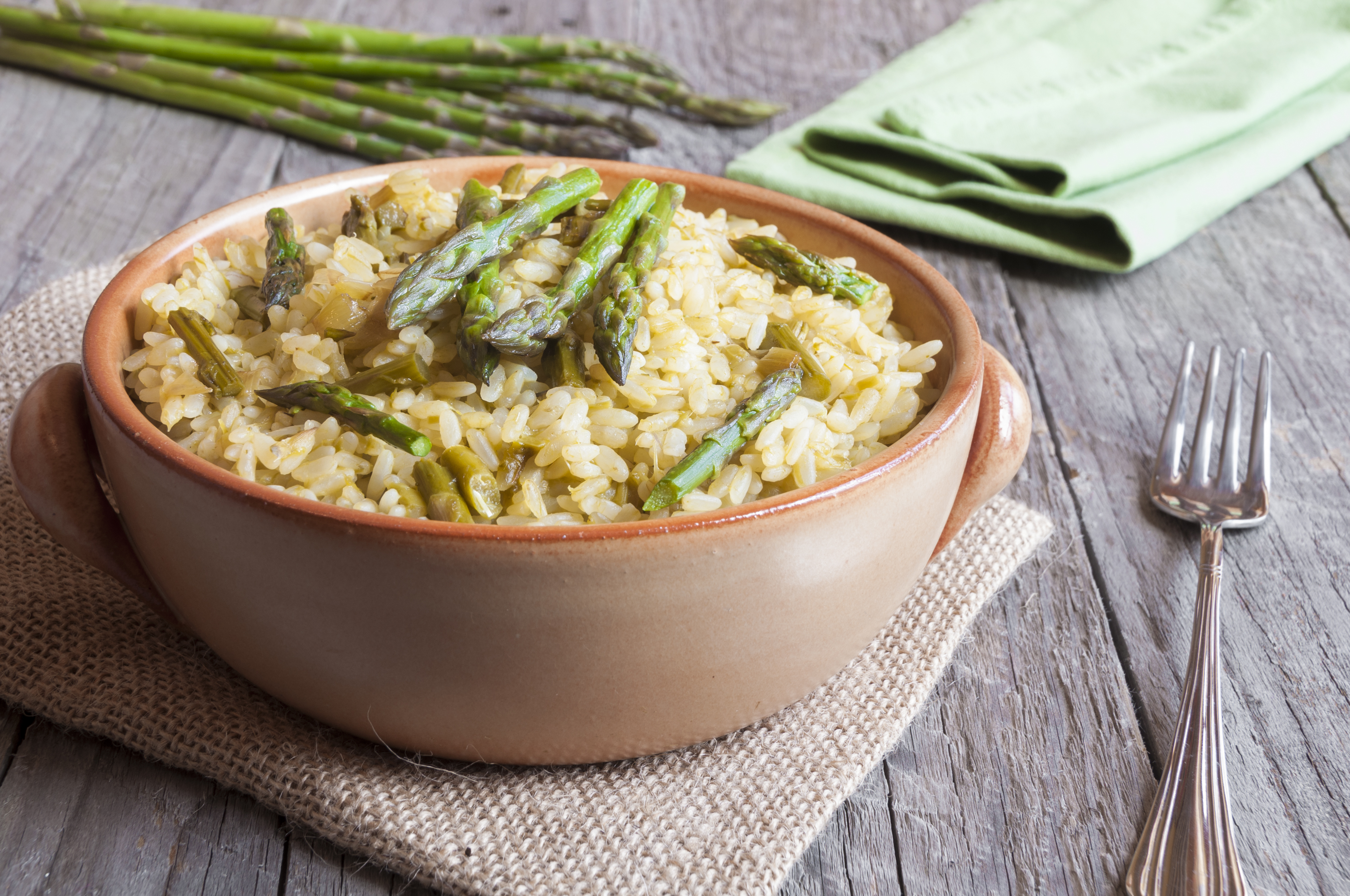 Skål med risotto toppad med sparris på ett bord