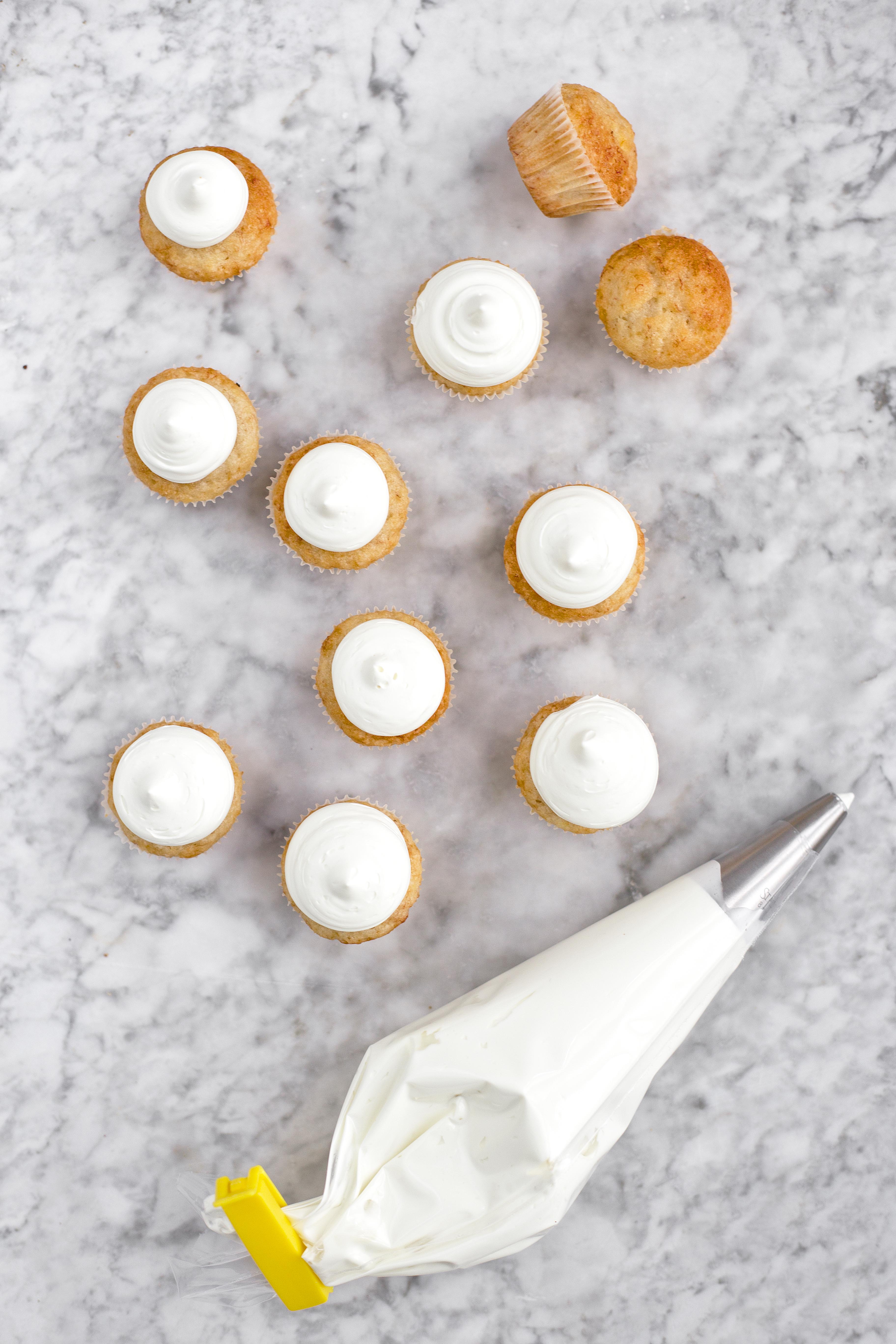 Bananmuffins med aquafaba har här gräddats i minimuffinsformar i 175°C i 13-15 minuter. Godisfluff av smälta bananskumgodisar är spritsat med en rund spritstyll på en centimeter.