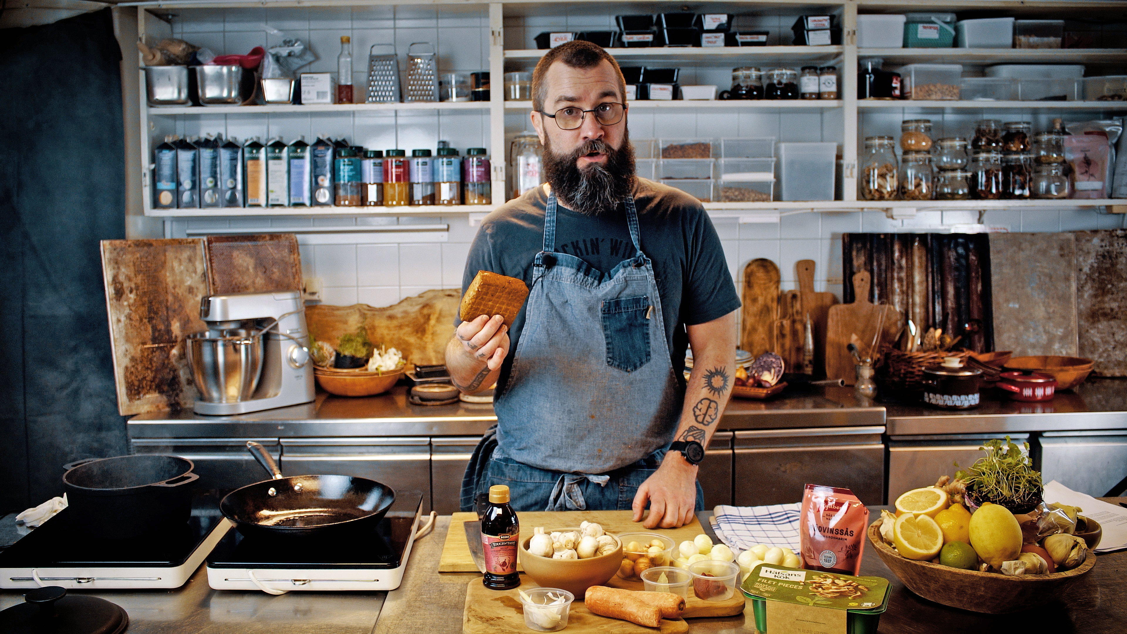 Fredrik Kämpenberg i ett kök med en tofu i handen