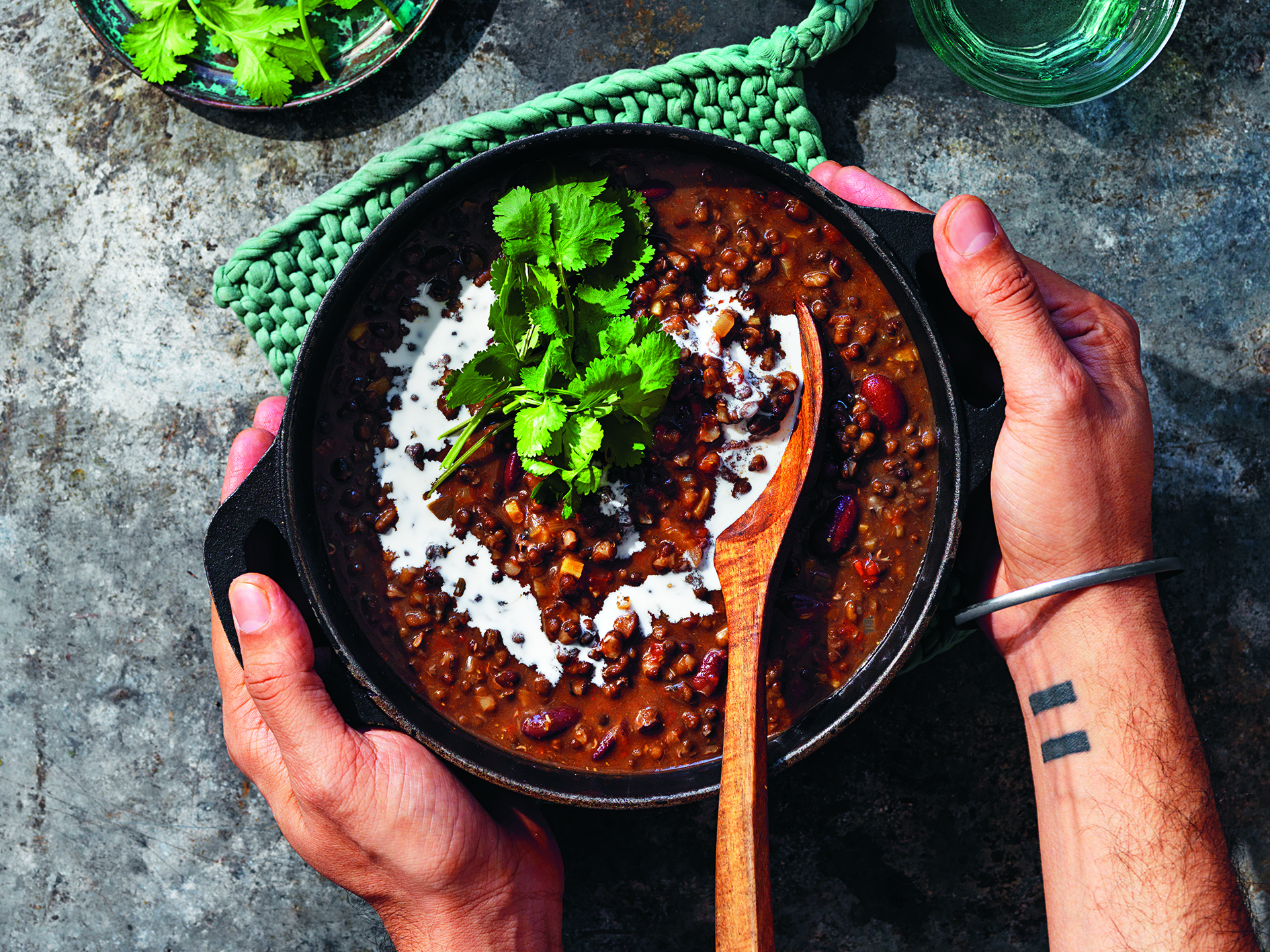 Dal makhani i gryta på bord. Två händer håller om grytan.