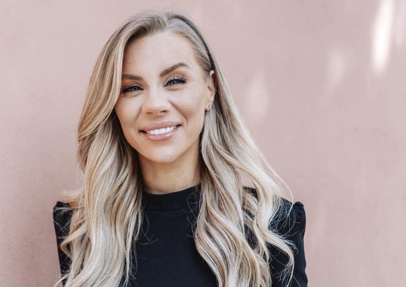 Therése Lindgren leendes framför beige vägg med solkatter
