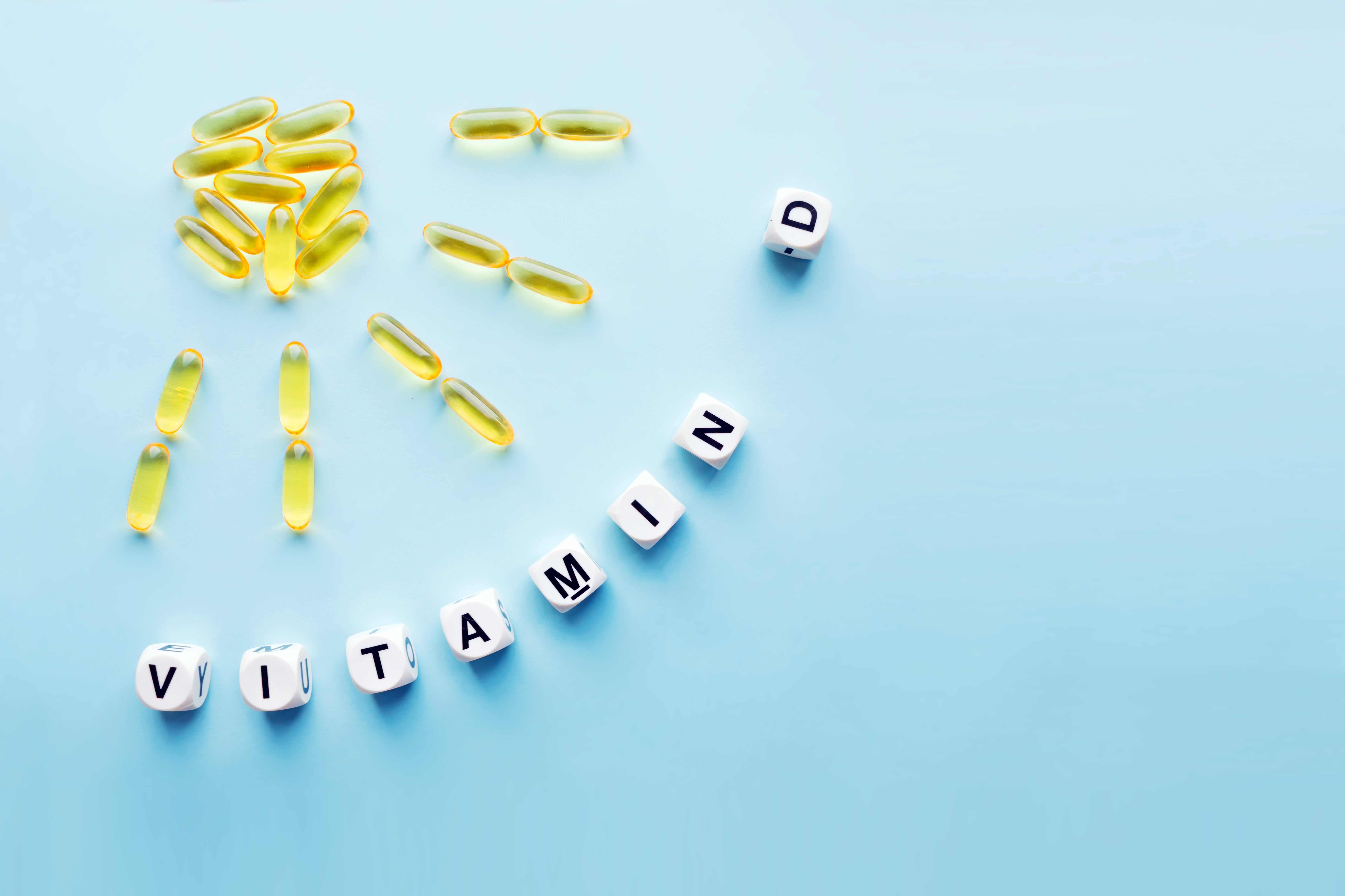 D vitaminpiller formade som en sol och tärningar med texten vitamin D mot en ljusbjå bakgrund