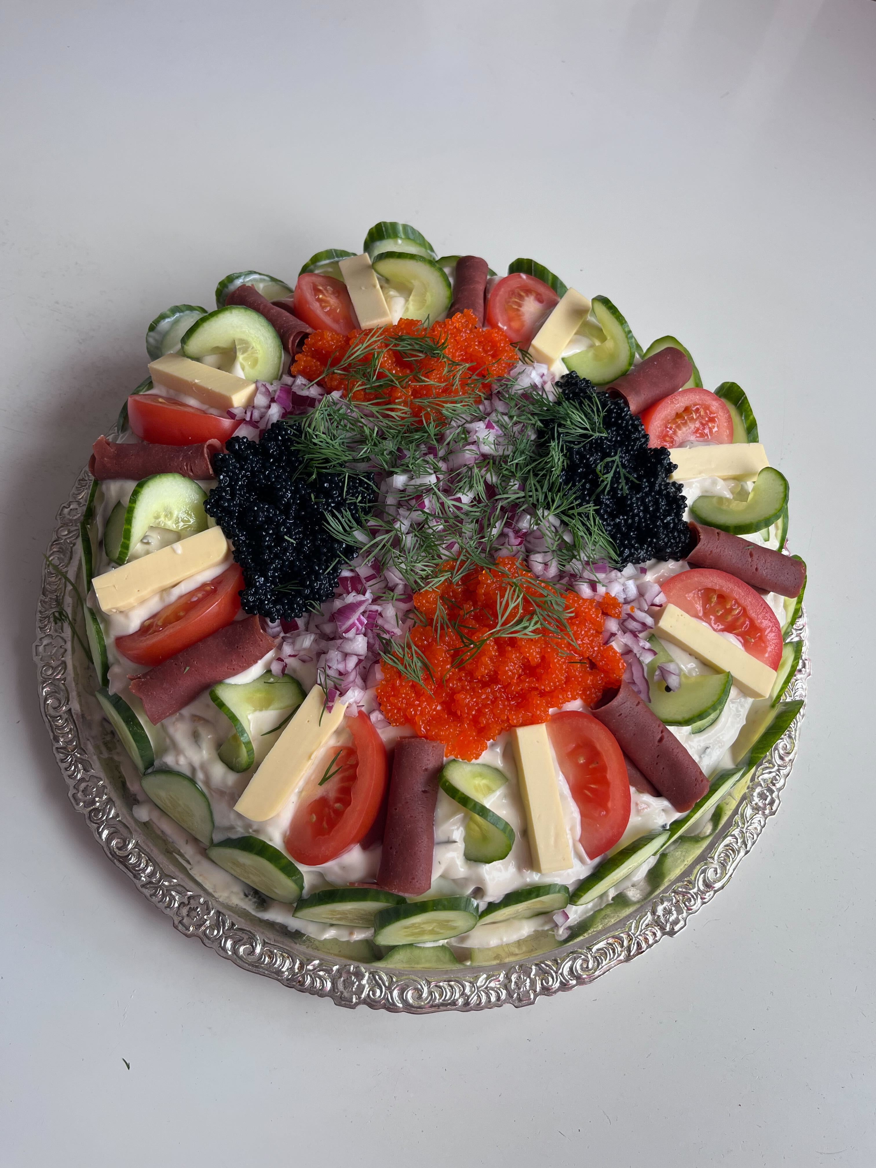 Vegansk smörgåstårta i rund form på ett silverfat.