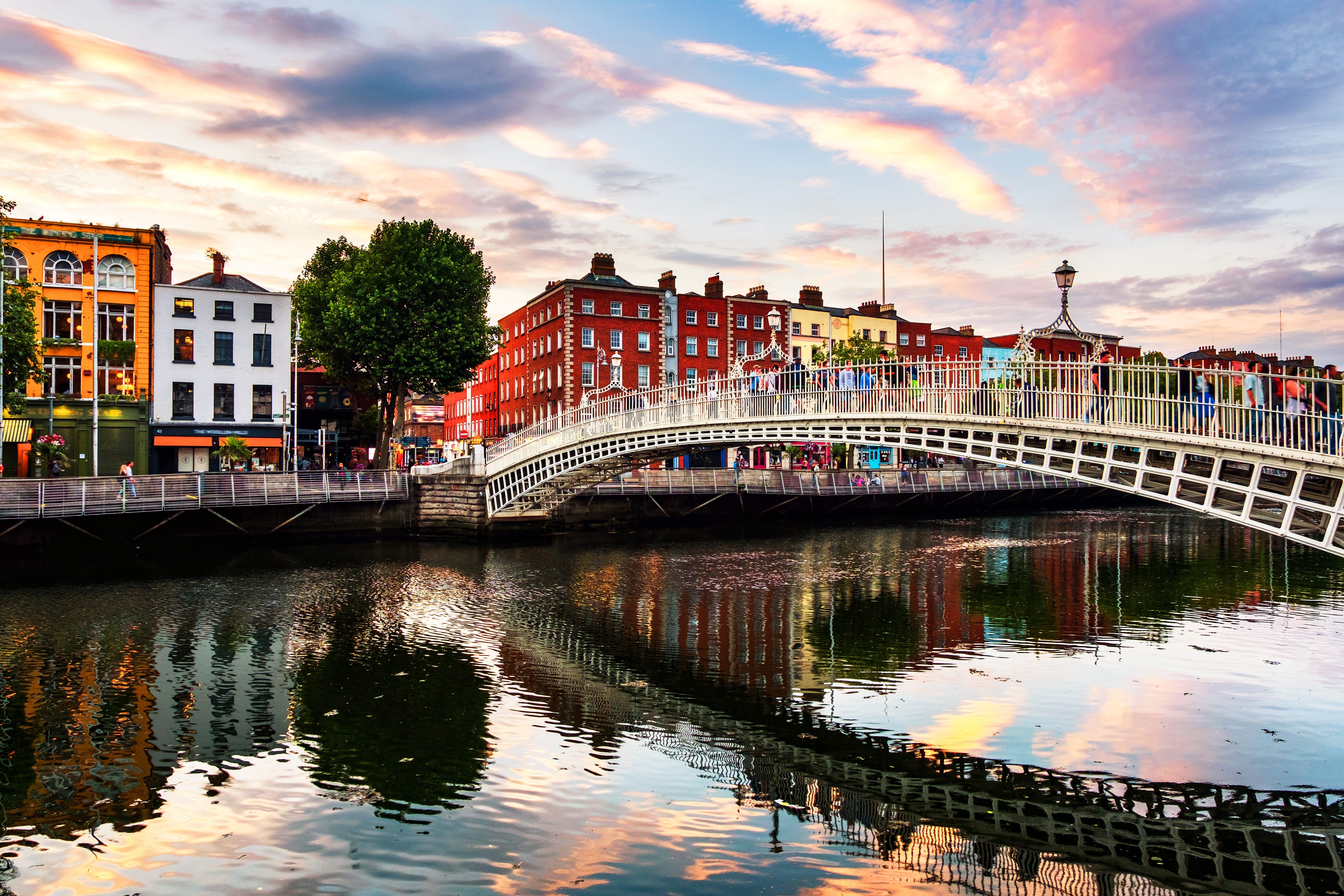Dublin, Irland. Nattutsikt över berömda upplysta Ha Penny Bridge i Dublin, Irland vid solnedgången.