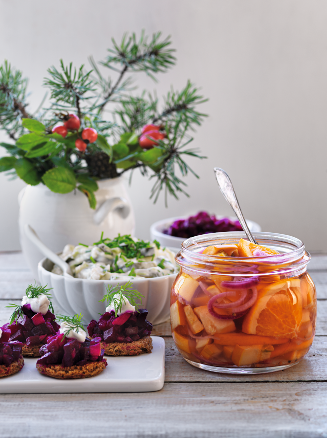 Picklad zucchini med apelsin i en glasburk bredvid snittar och vas med blomster