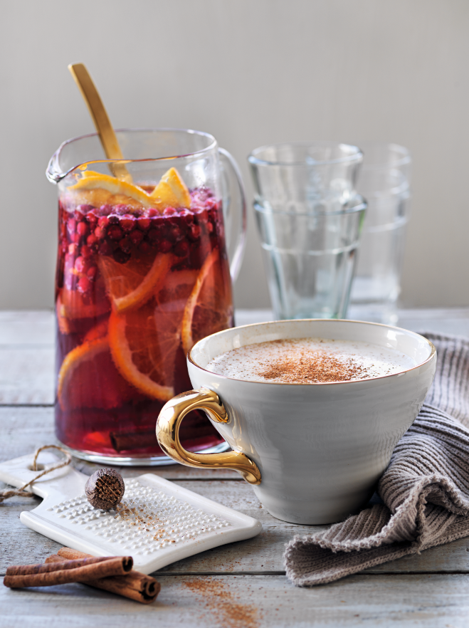 Toddy i en vit mugg med guldhandtag bredvid en karaff med sangria.