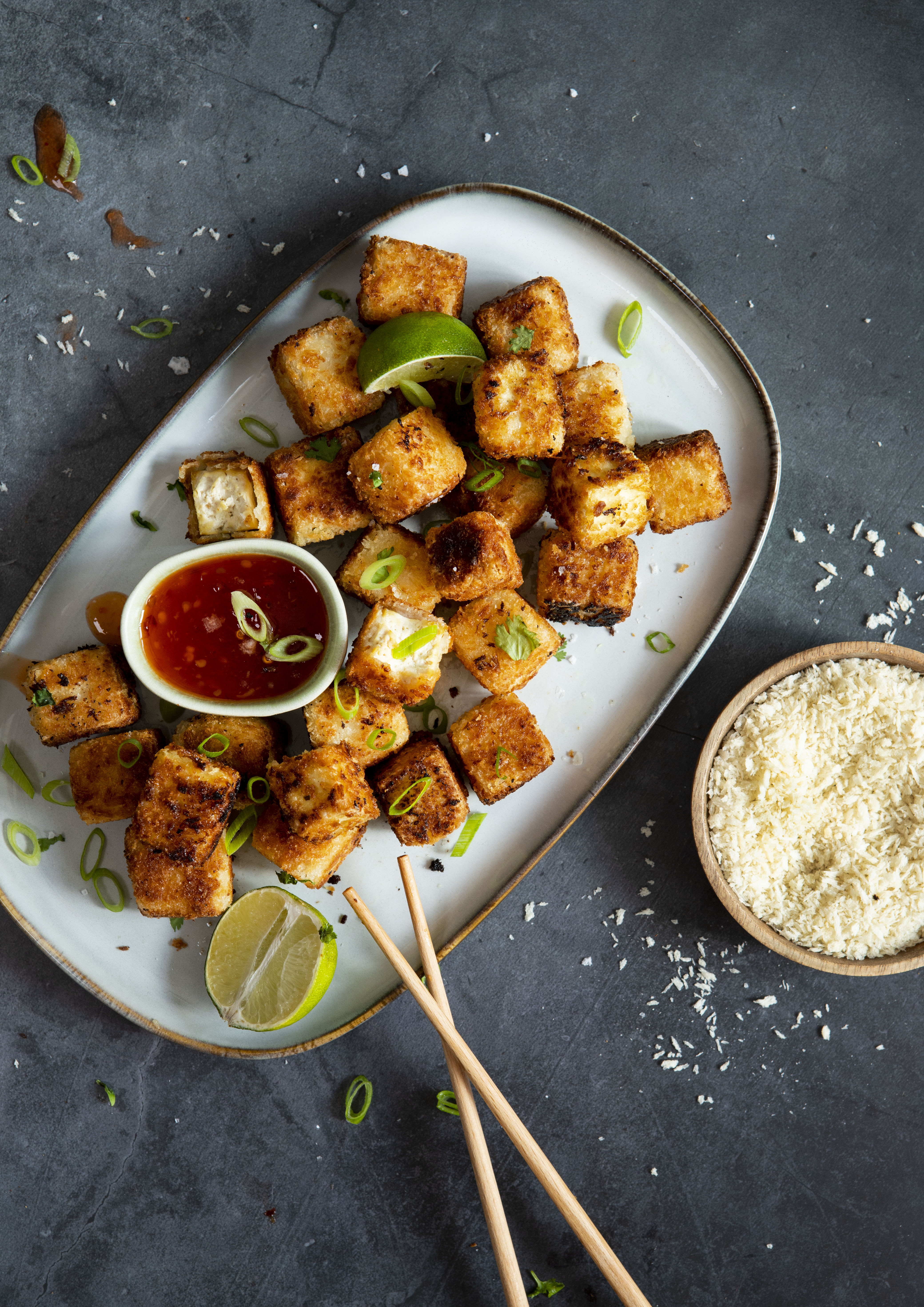 Panerad tofu på ett ljust serveringsfat mot en mörk bakgrund.