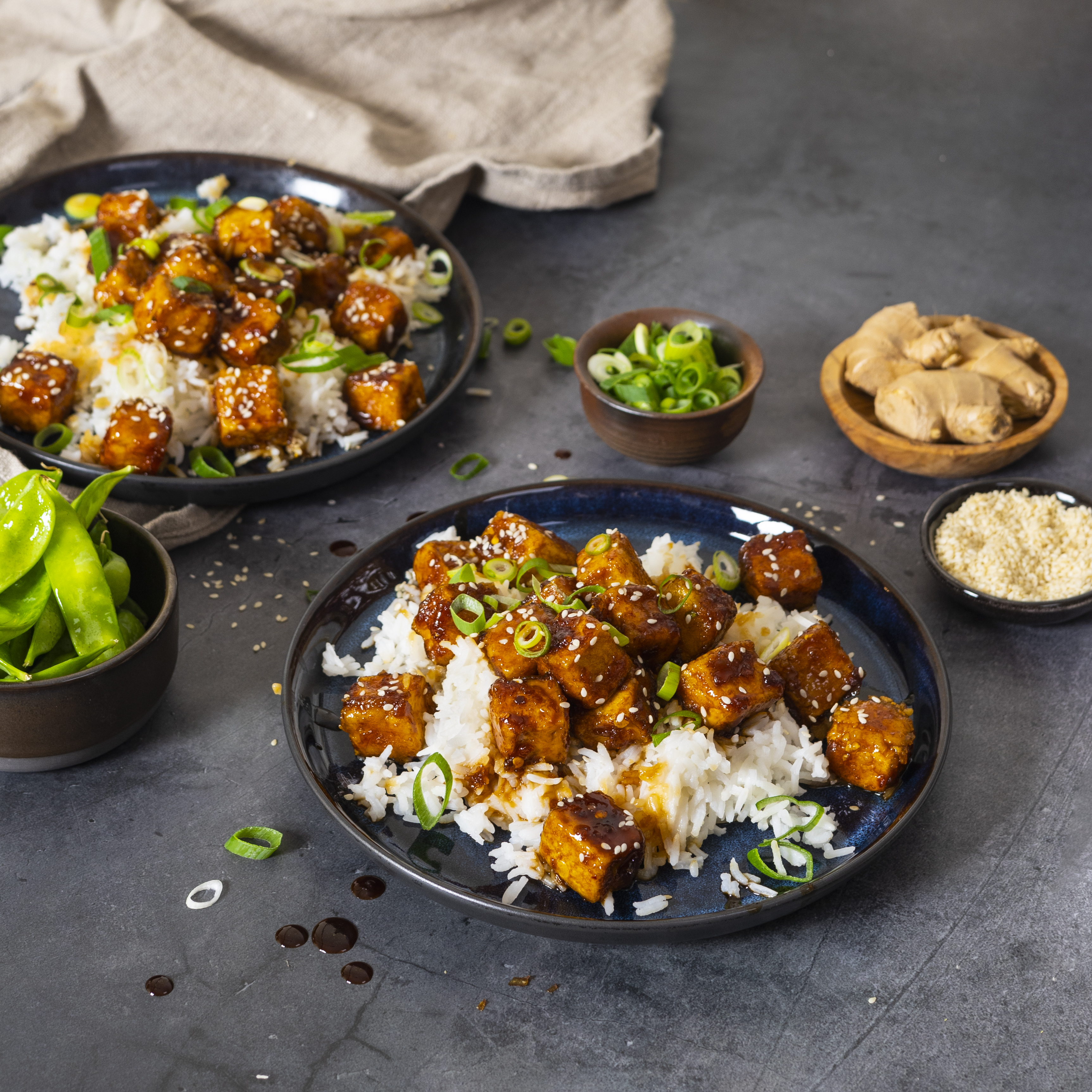 Två djuptallrikar med general tso tofu på ett mörkgrått bord