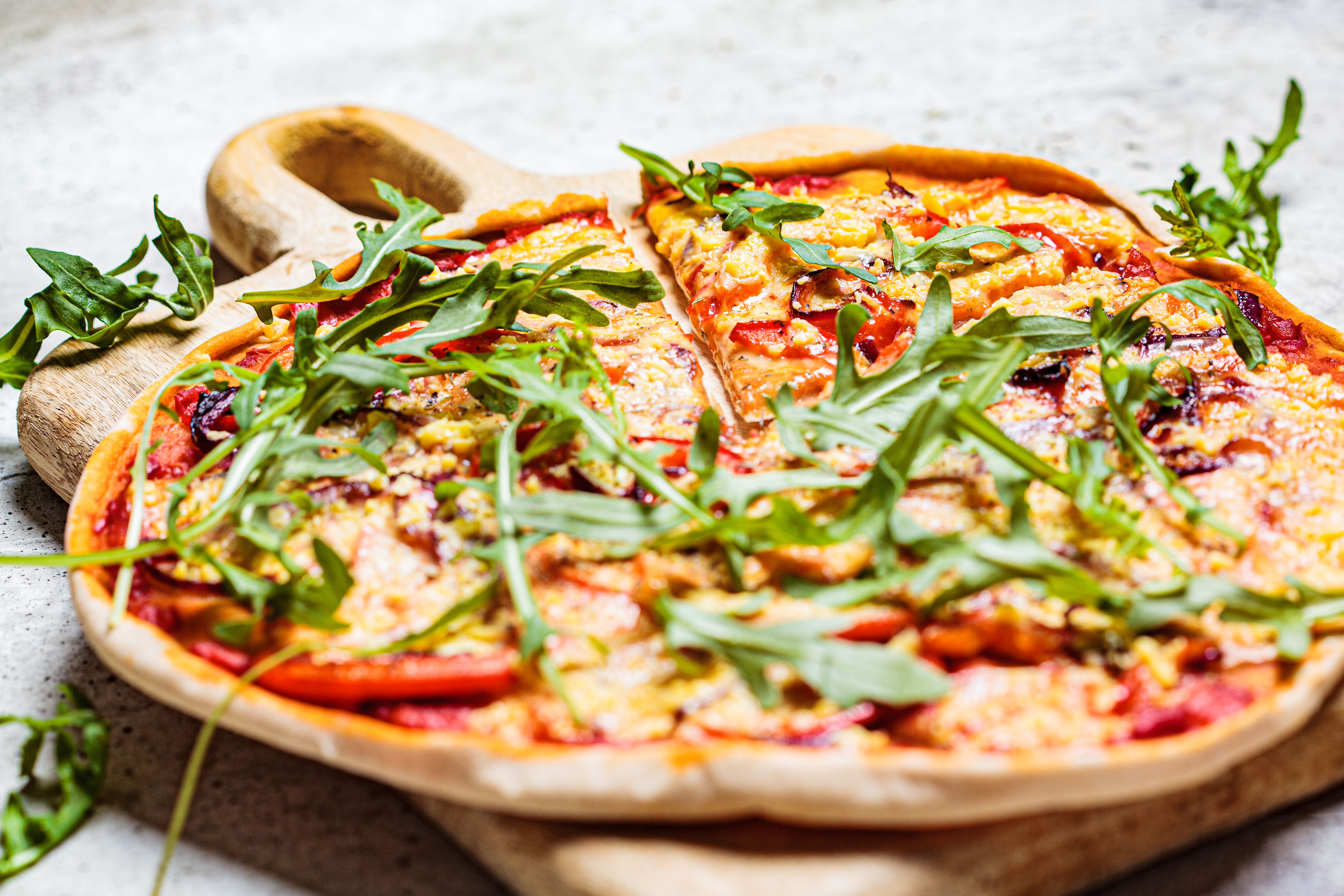 Vegan pizza with tomato sauce, pepper, vegan cheese and arugula. Healthy vegan food concept.