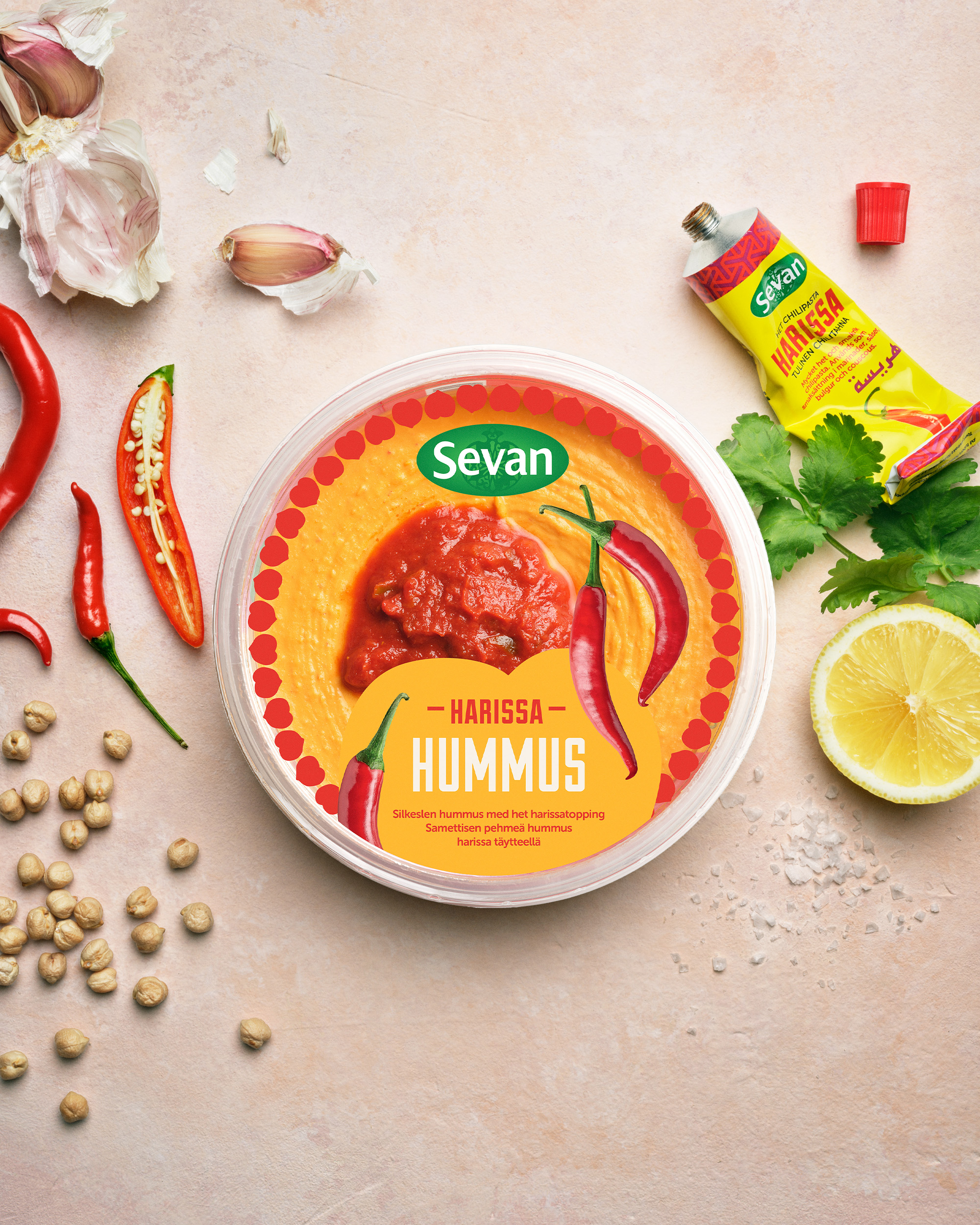 En burk med hummus på ett bort med citron, mynta, vitlök och kikärtor runt