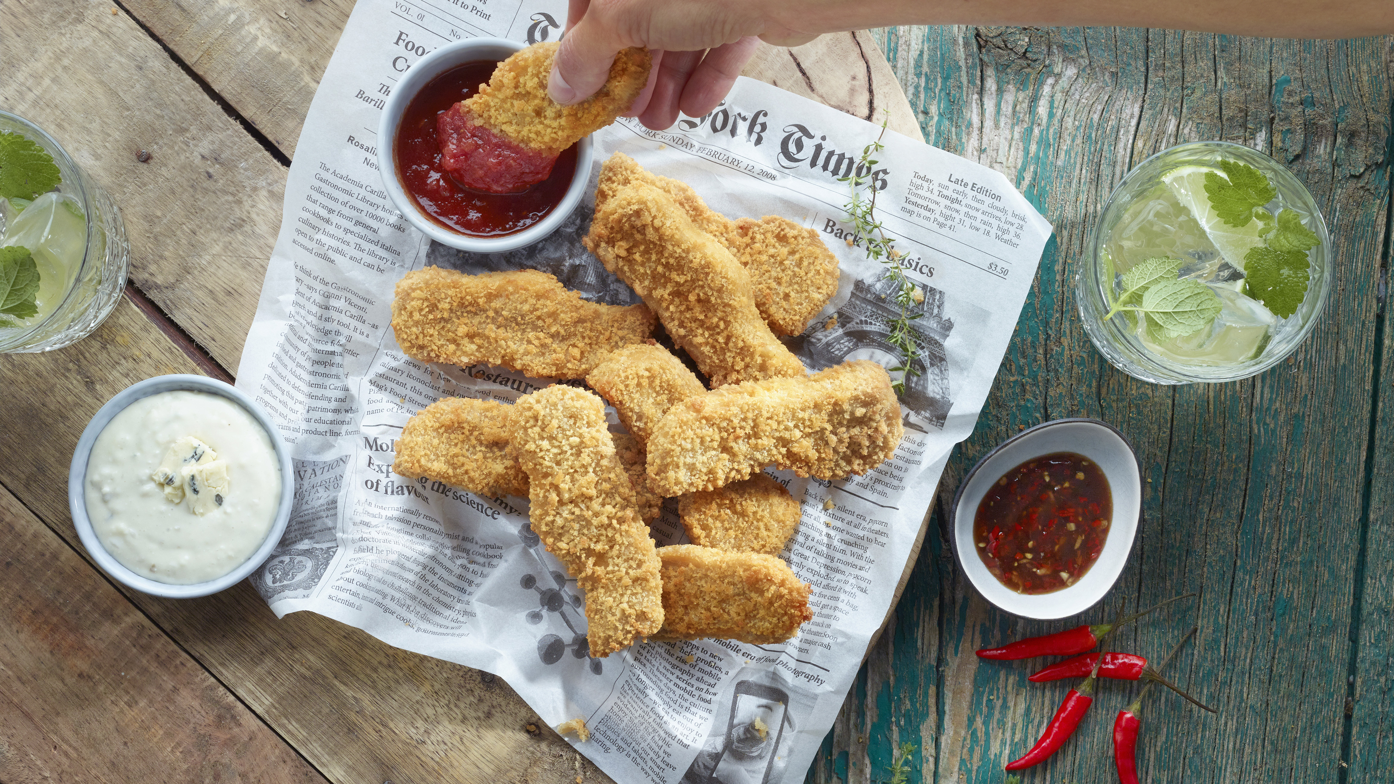 Veganska chicken fingers på ett tidningspapper med massa dippar runt om.