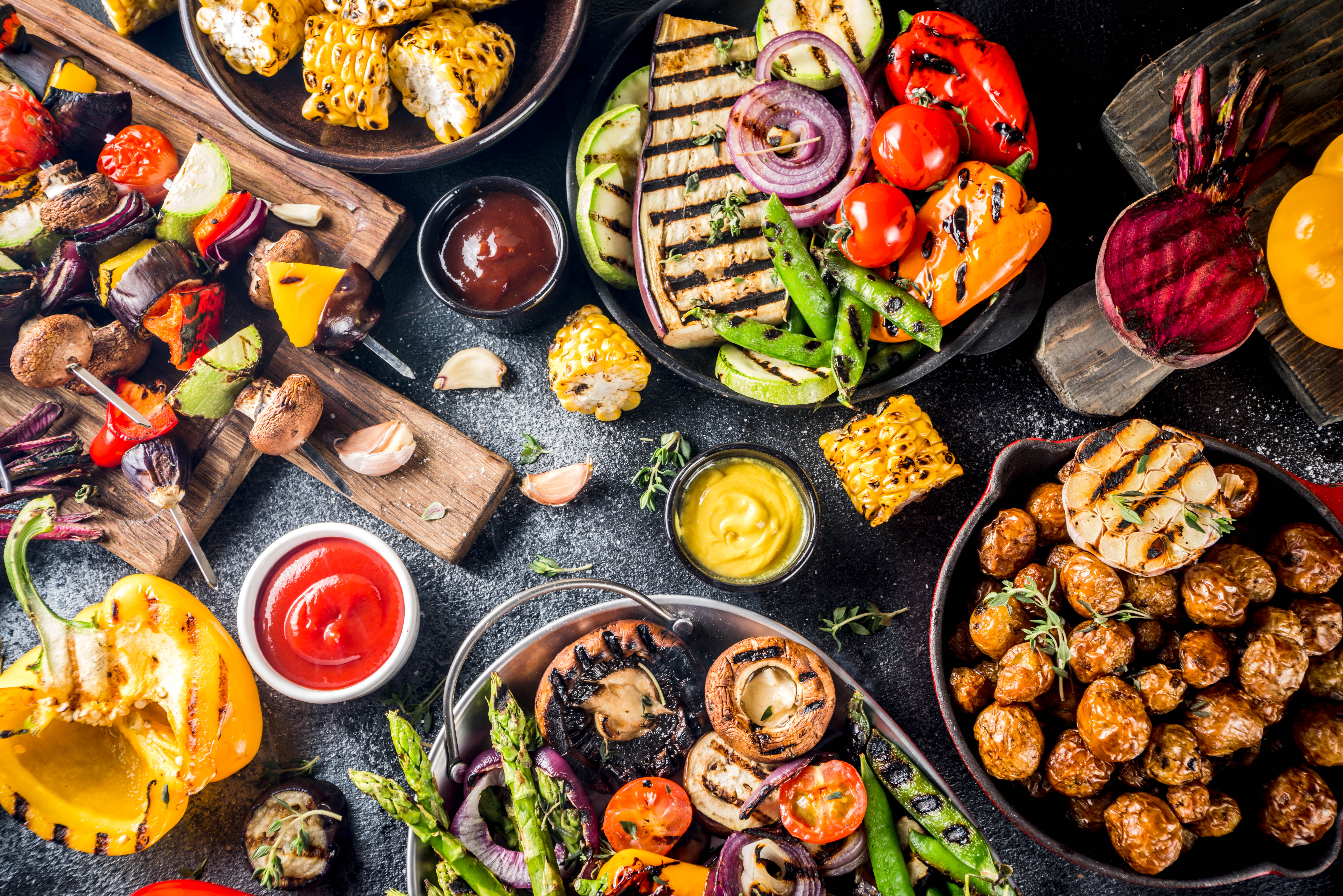 Ett bord fullt med grillade grönsaker och veganska tillbehör