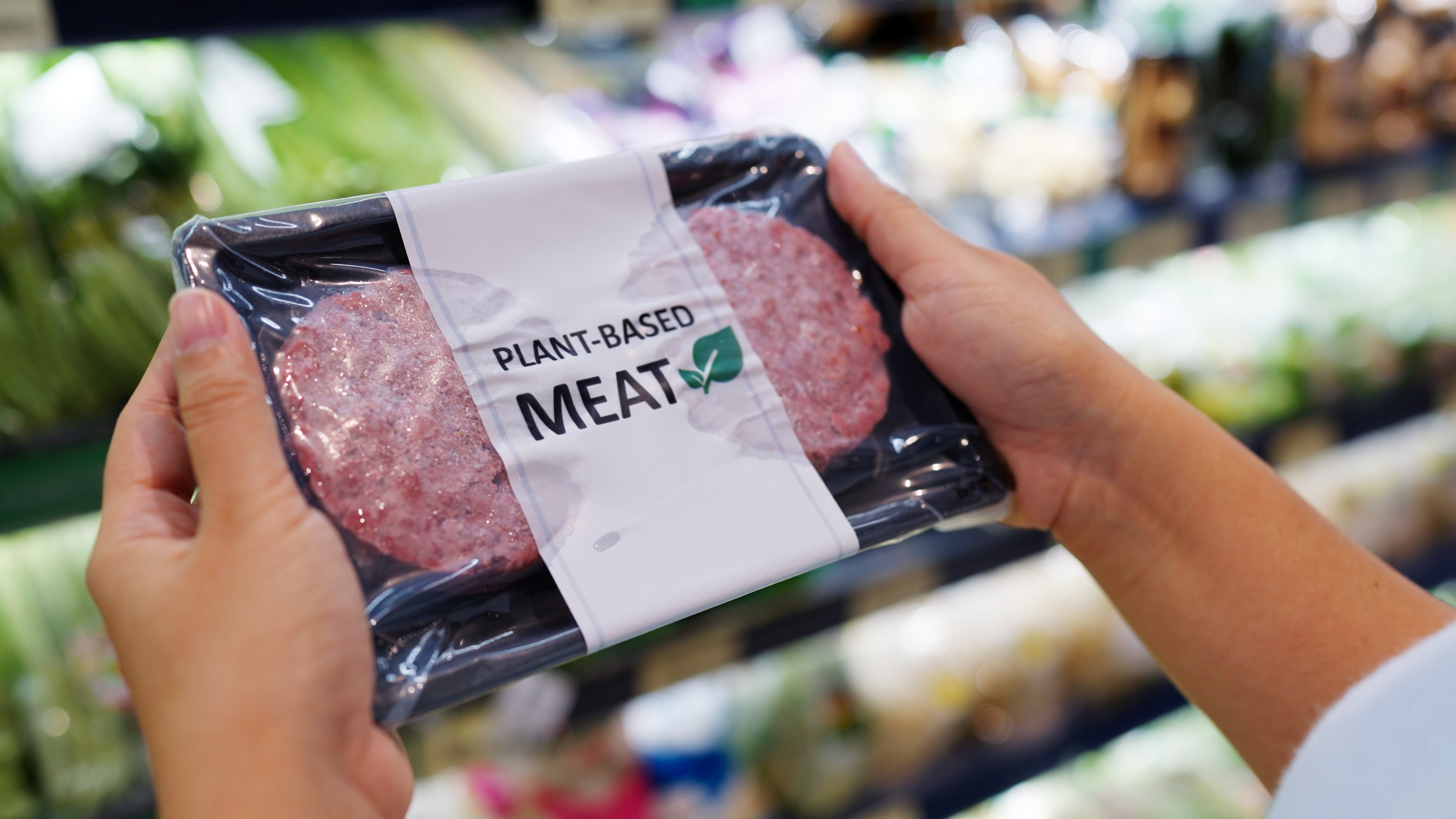 Händer som håller i en förpackning vegansk kött i en butik