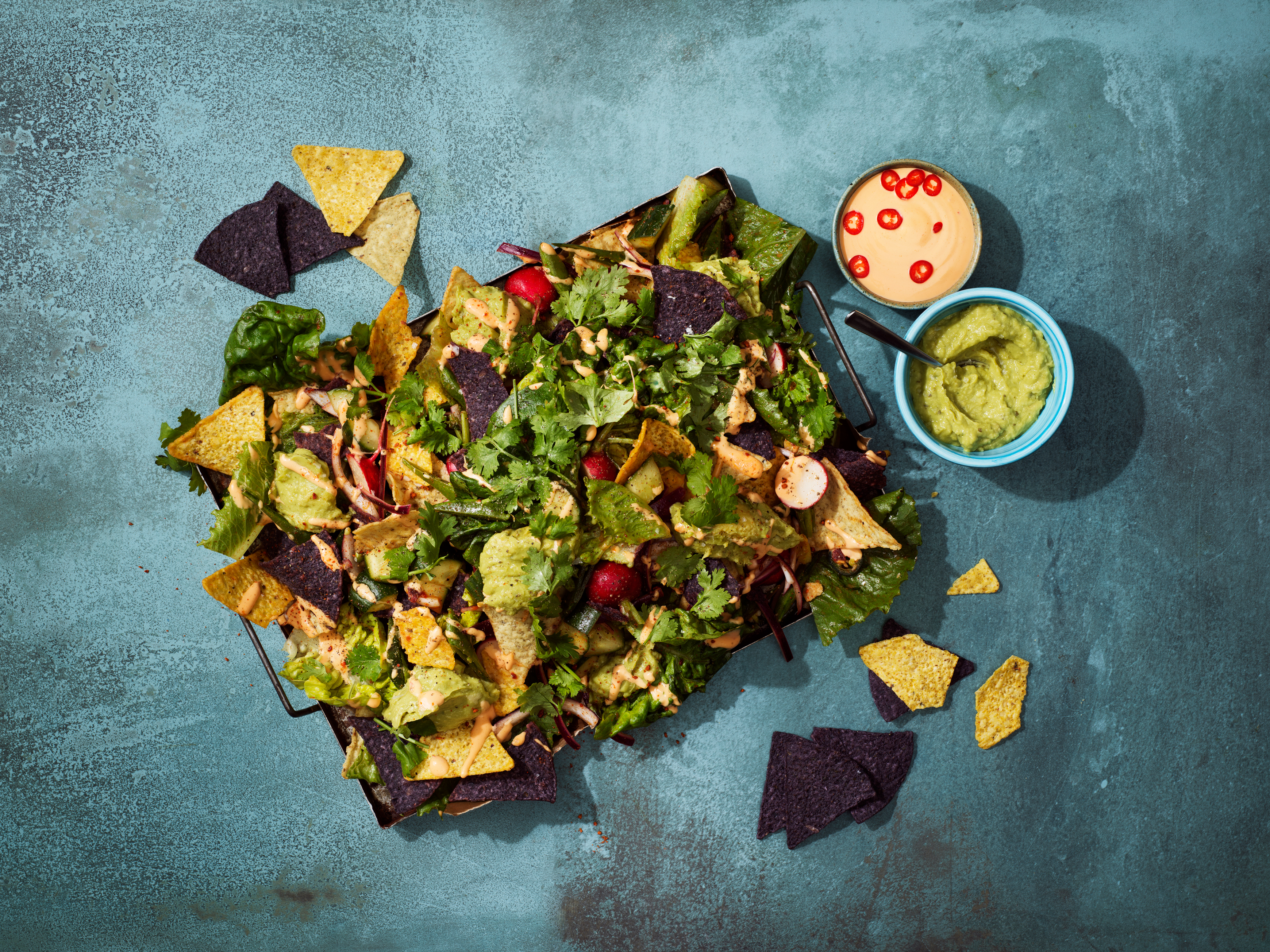 en bricka med nachos och topping på ett mörgrått bord