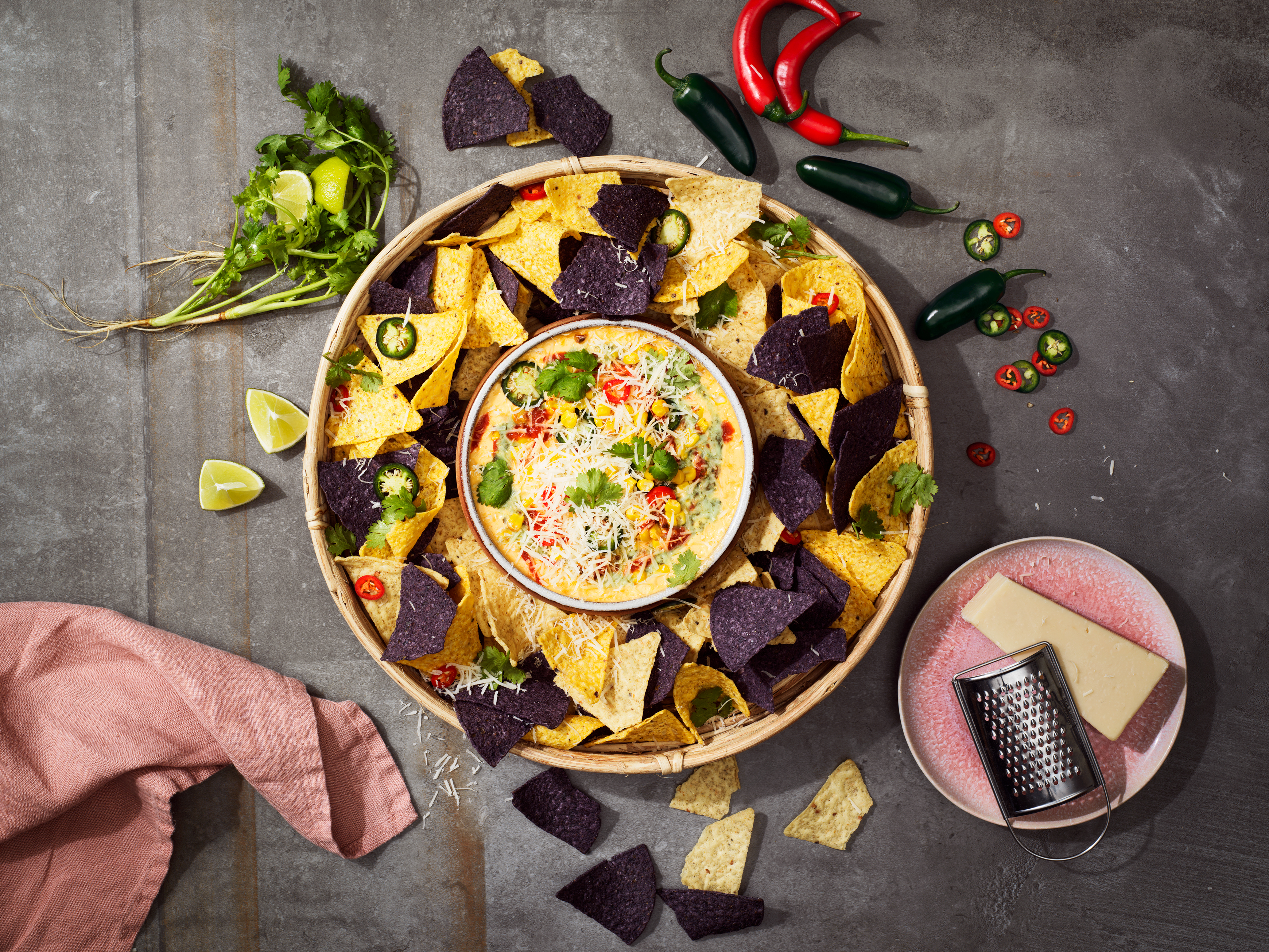 En skål med nachos och en liten skål med vegansk ostdipp mitt i den stora nachoskålen