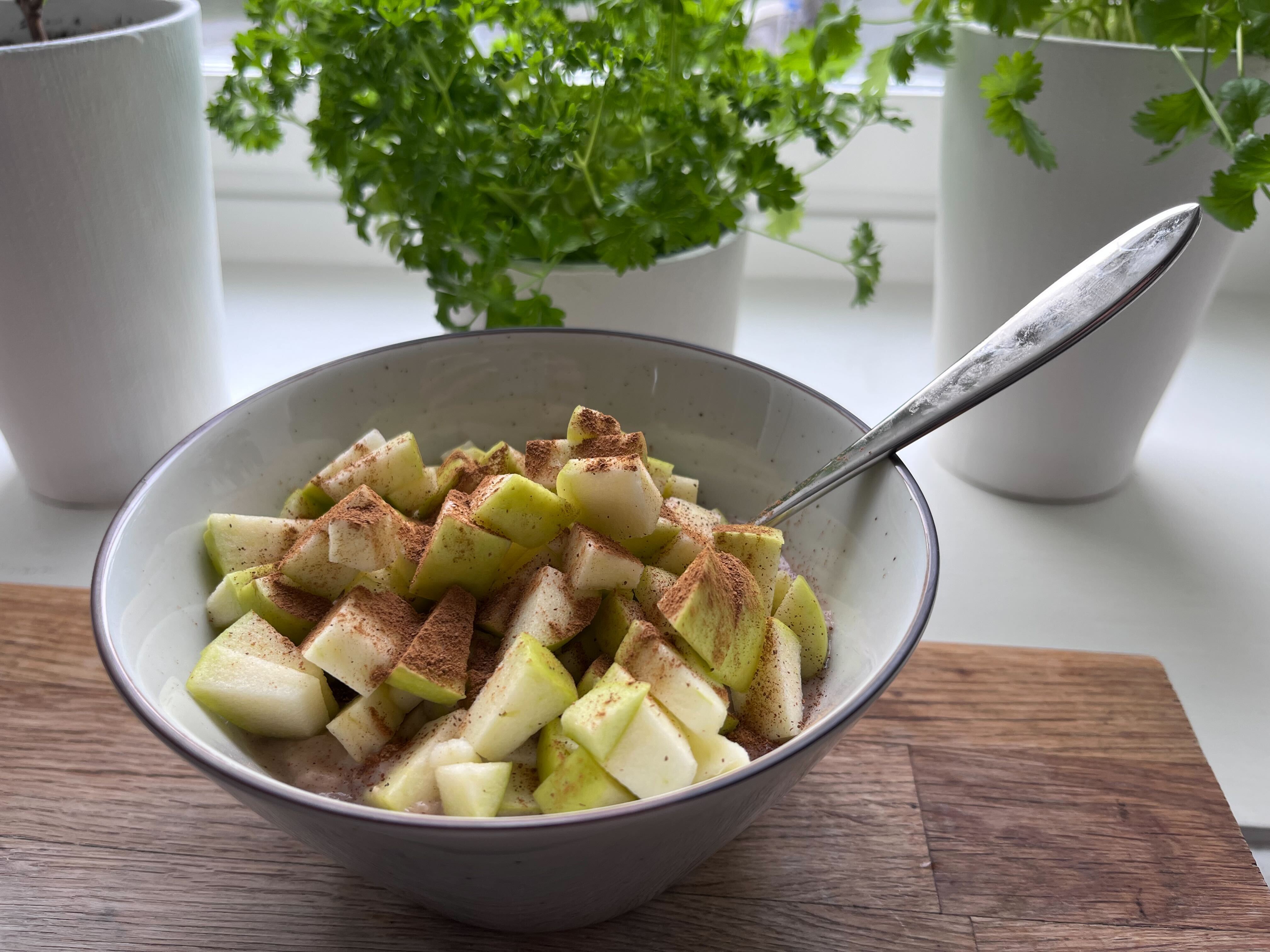 gröt med äpple i en skål på ett träbord