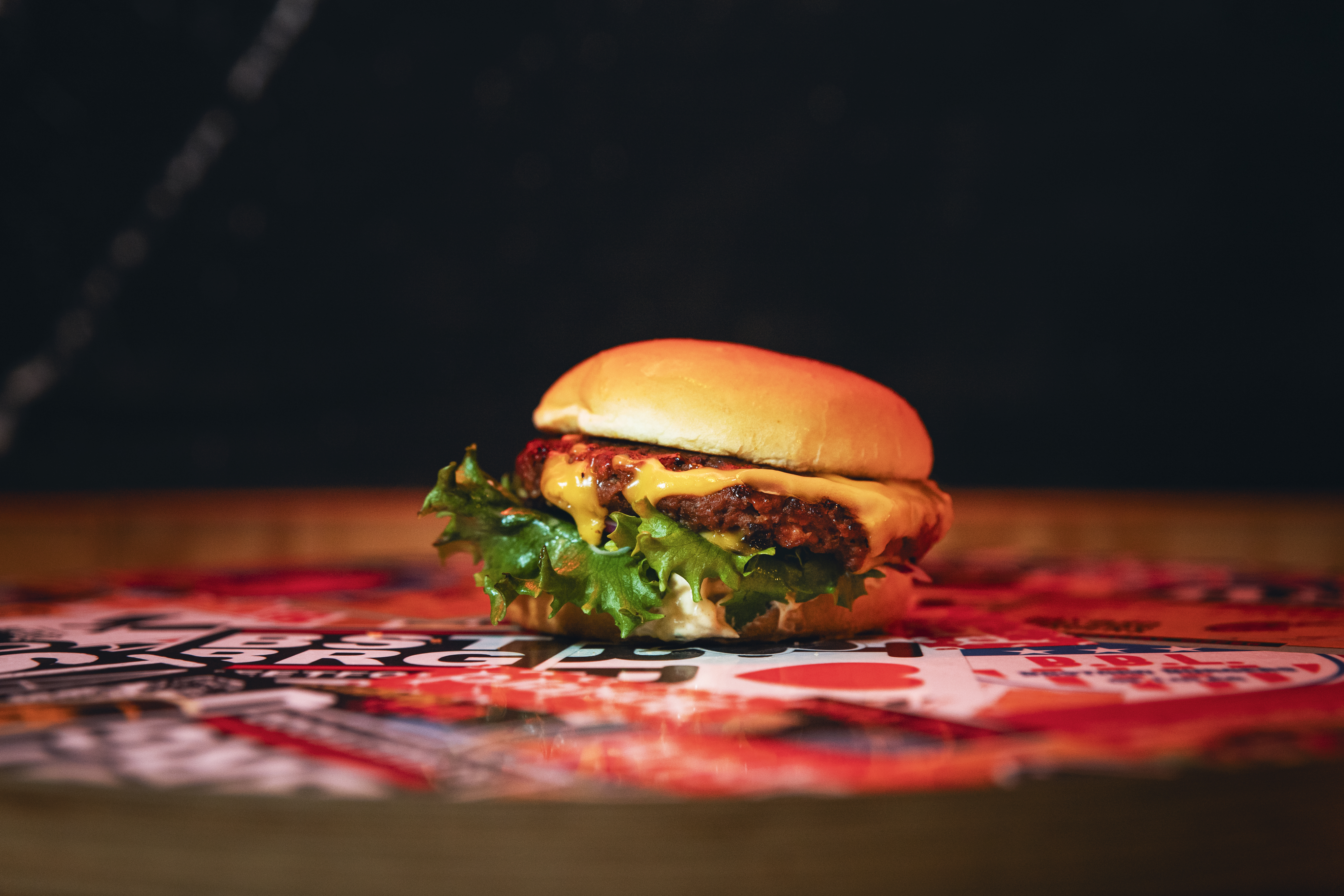 En vegansk hamburgare på ett färgglatt bord och en mörk bakgrund