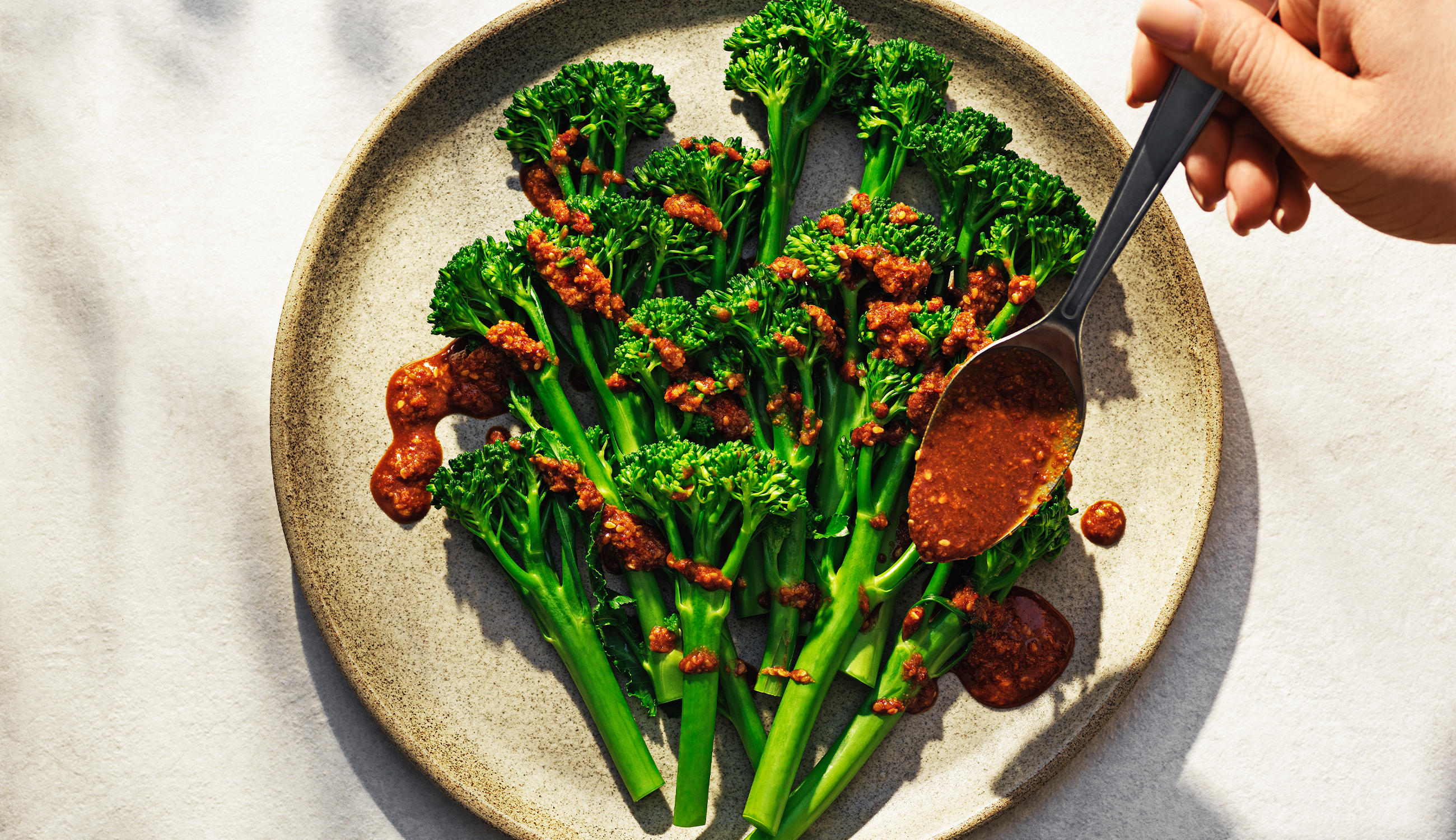 Ångad broccoli på en tallrik med dressing över