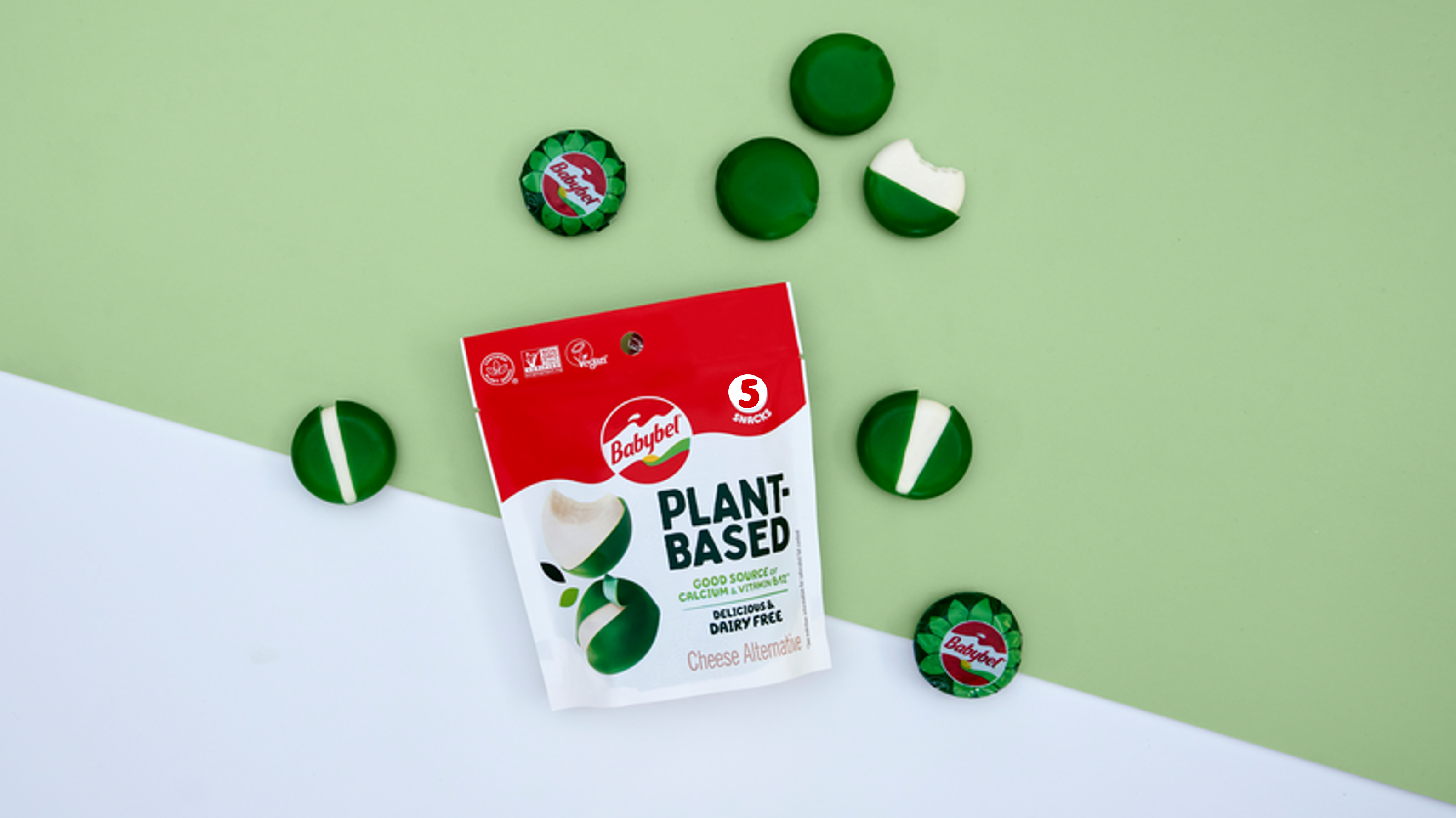 En förpackning växtbaserade ostar från Babybel på en grön och vit bakgrund, bild tagen uppifrån.