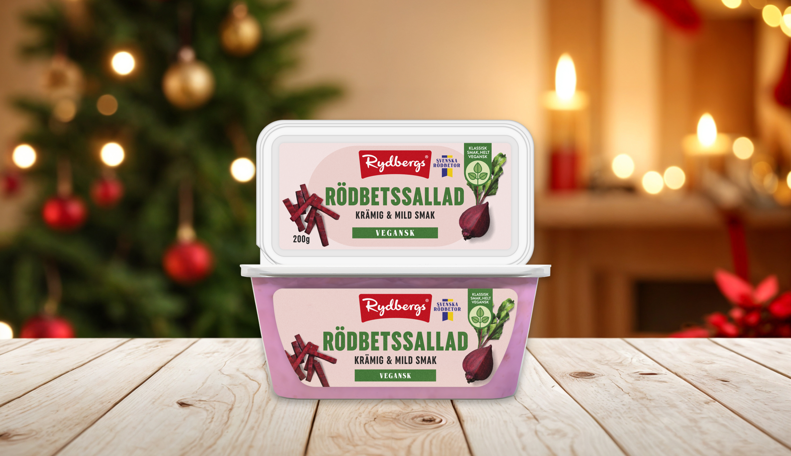 två förpackningar vegansk rödbetssallad staplade på varanda på ett träbord med en julig bakgrund