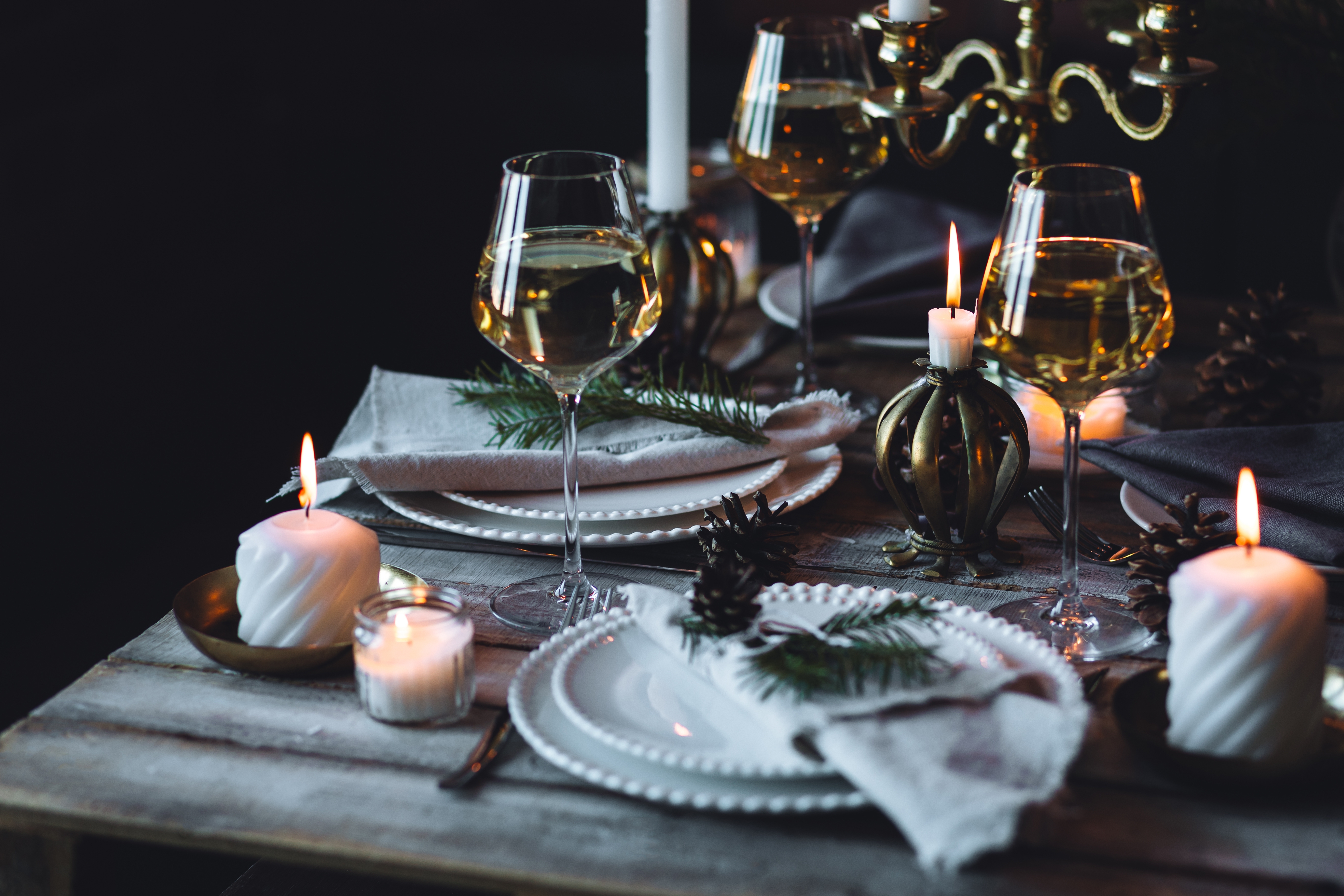 Rustic Scandinavian style zero waste eco-friendly dinner table decor for Christmas or new year family celebration. Wooden table, natural elements like pine cones, fir tree branches, candles