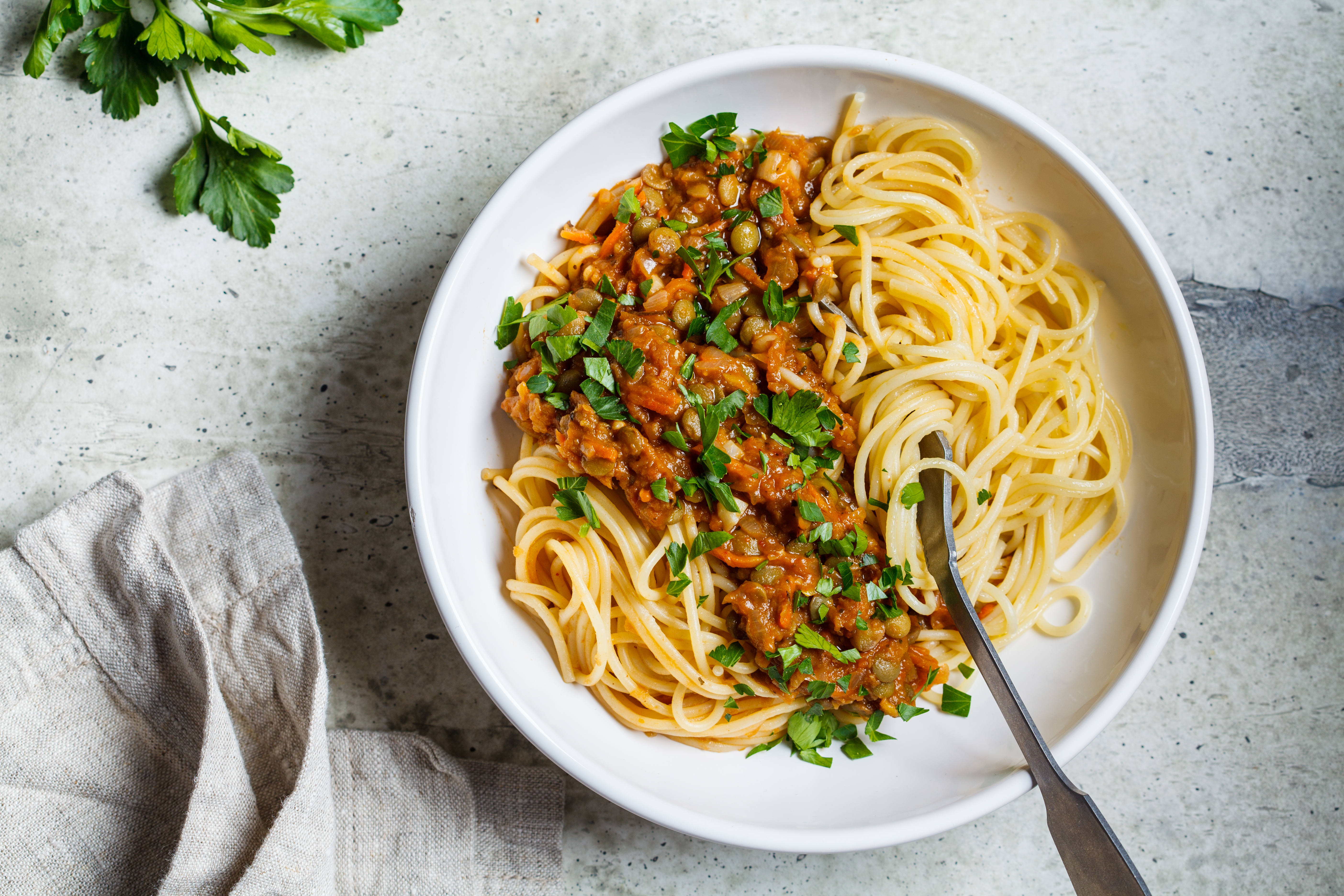 Vegansk bolognese på linser med spaghetti i en vit tallrik på ett bord