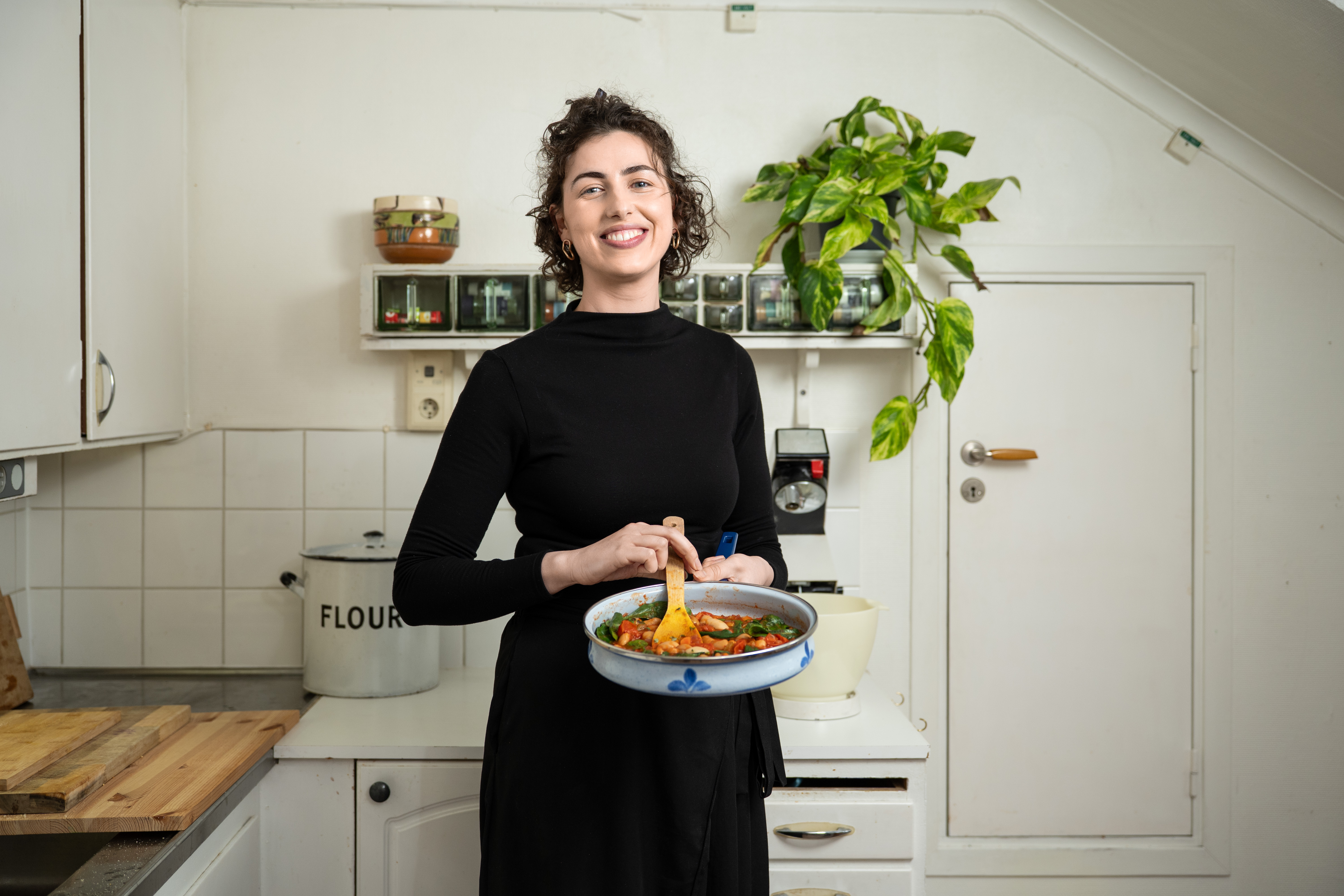 Kvinna i ett kök som håller i en gryta med mat