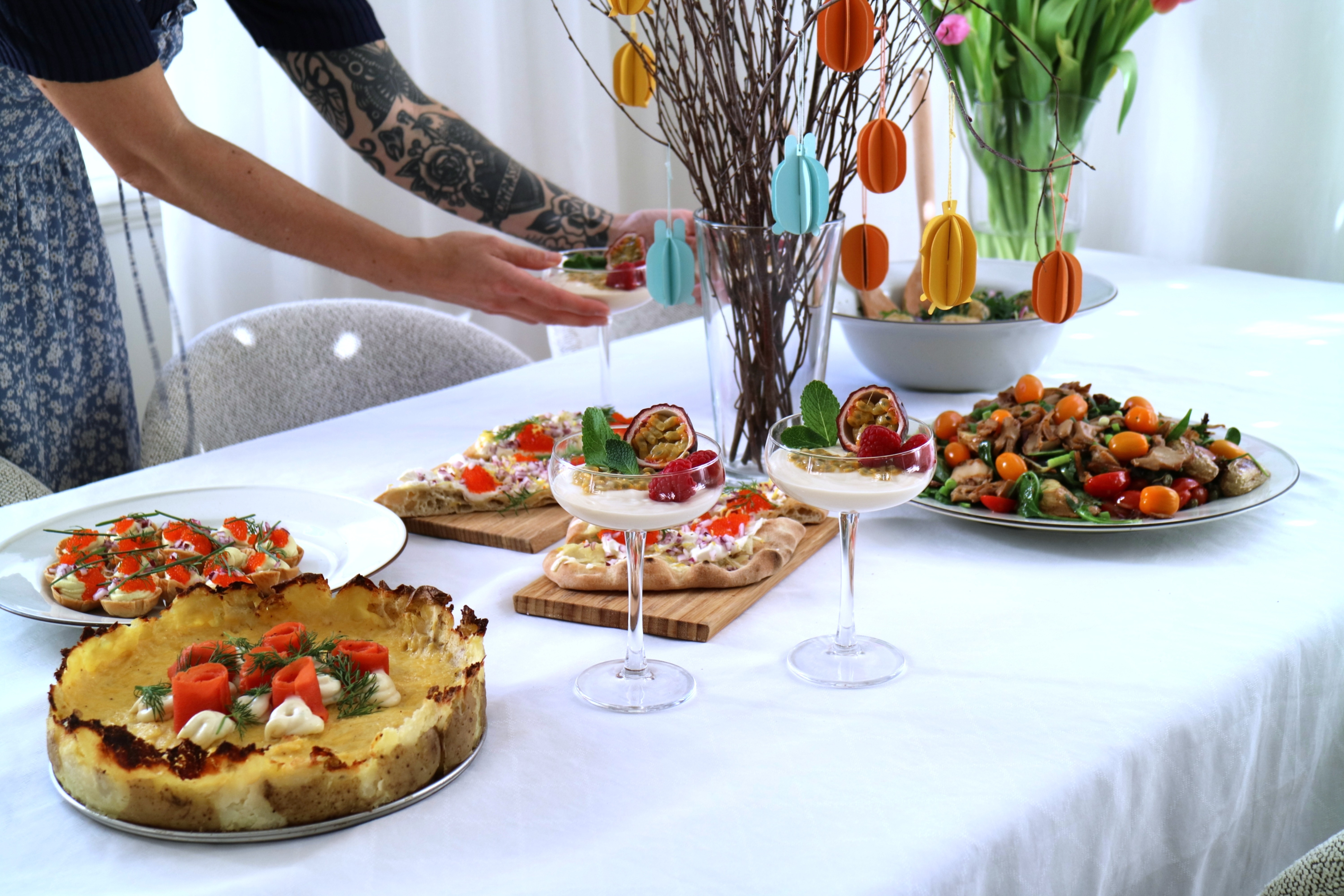 Veganskt påskbord och tjej med en tatuerad arm som håller i cocktailglas