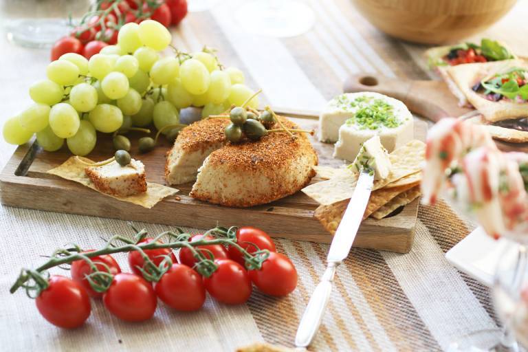 Veganska cashewostar på en bricka intill vindruvor