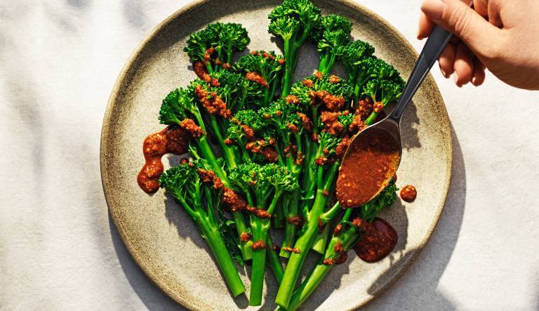 Ångad broccoli på en tallrik med dressing över