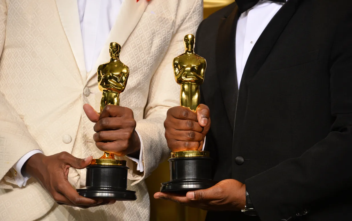 Två personer håller i varsin oscarstatyett