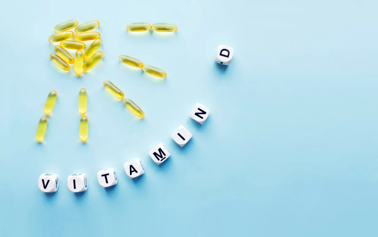 D vitaminpiller formade som en sol och tärningar med texten vitamin D mot en ljusbjå bakgrund