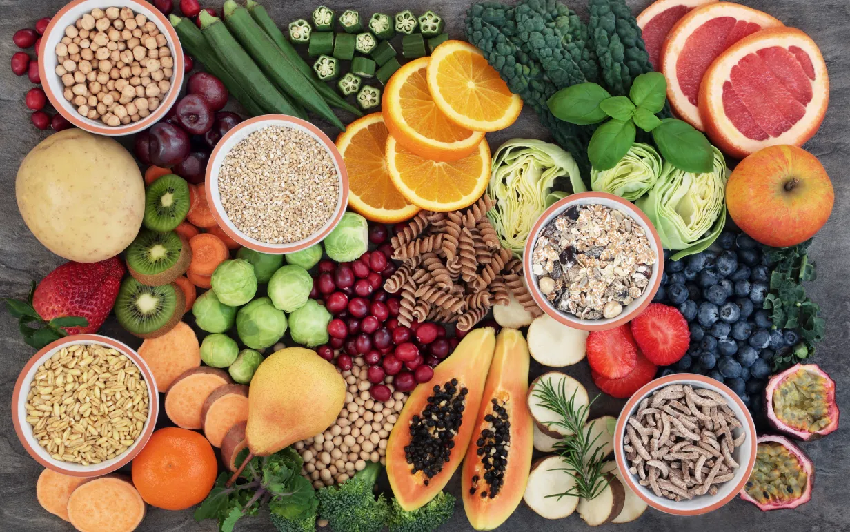 Hälsomat koncept för en högfiberdiet med frukt, grönsaker, spannmål, fullkornspasta, korn, baljväxter och örter.