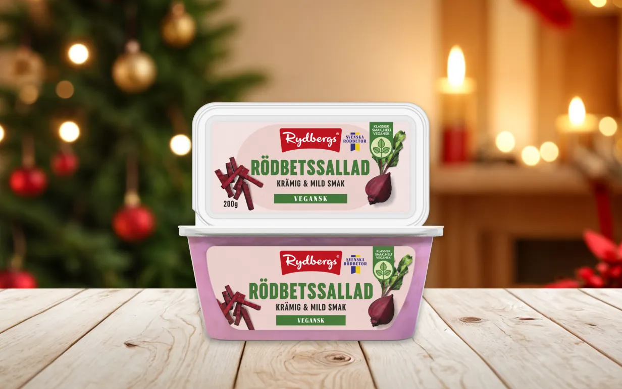 två förpackningar vegansk rödbetssallad staplade på varanda på ett träbord med en julig bakgrund