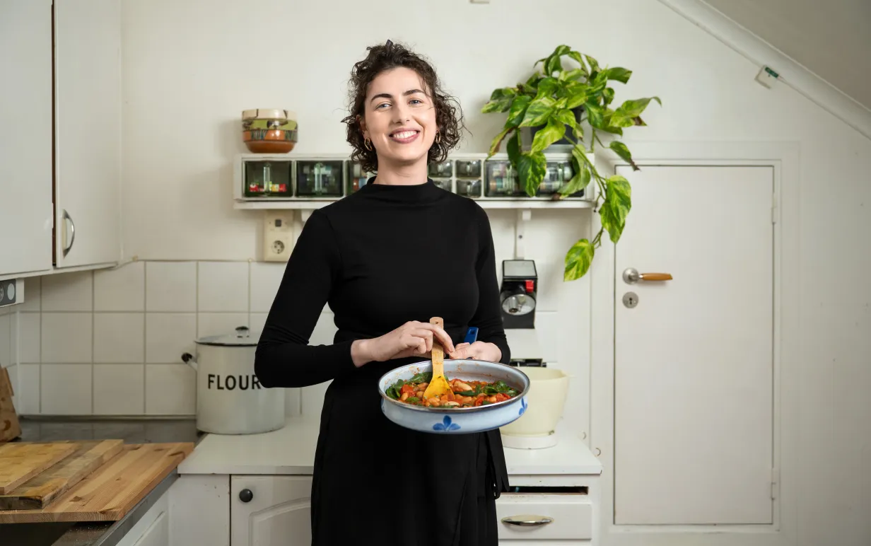 Kvinna i ett kök som håller i en gryta med mat