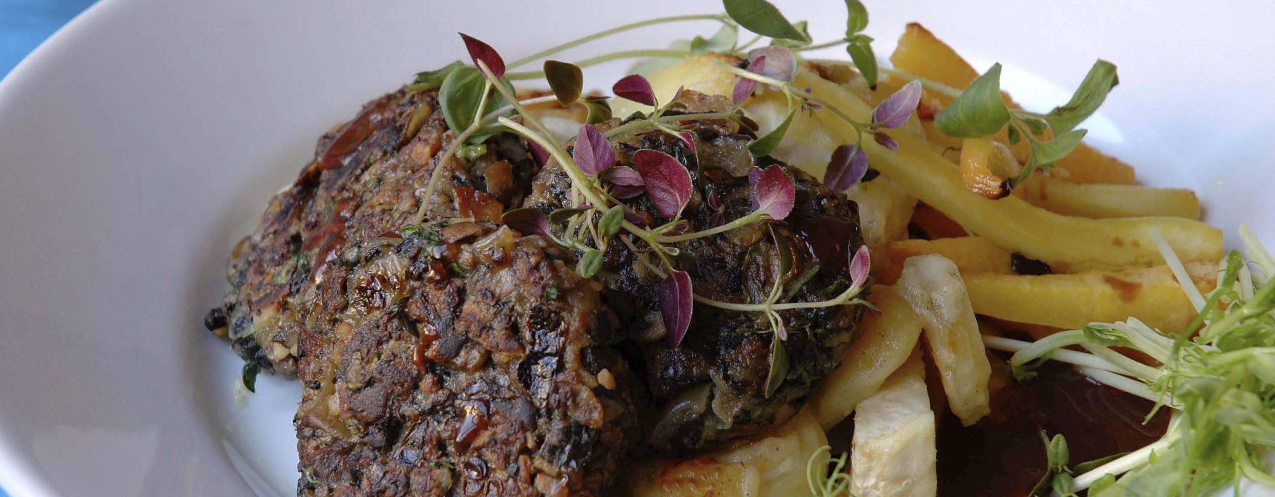 Veganska svampbiffar med sås och potatis på en vit tallrik.