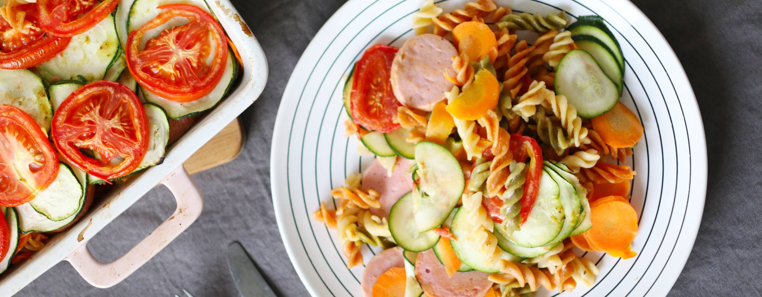 Vegansk pastagratäng på en tallrik intill en form med mer pastagratäng