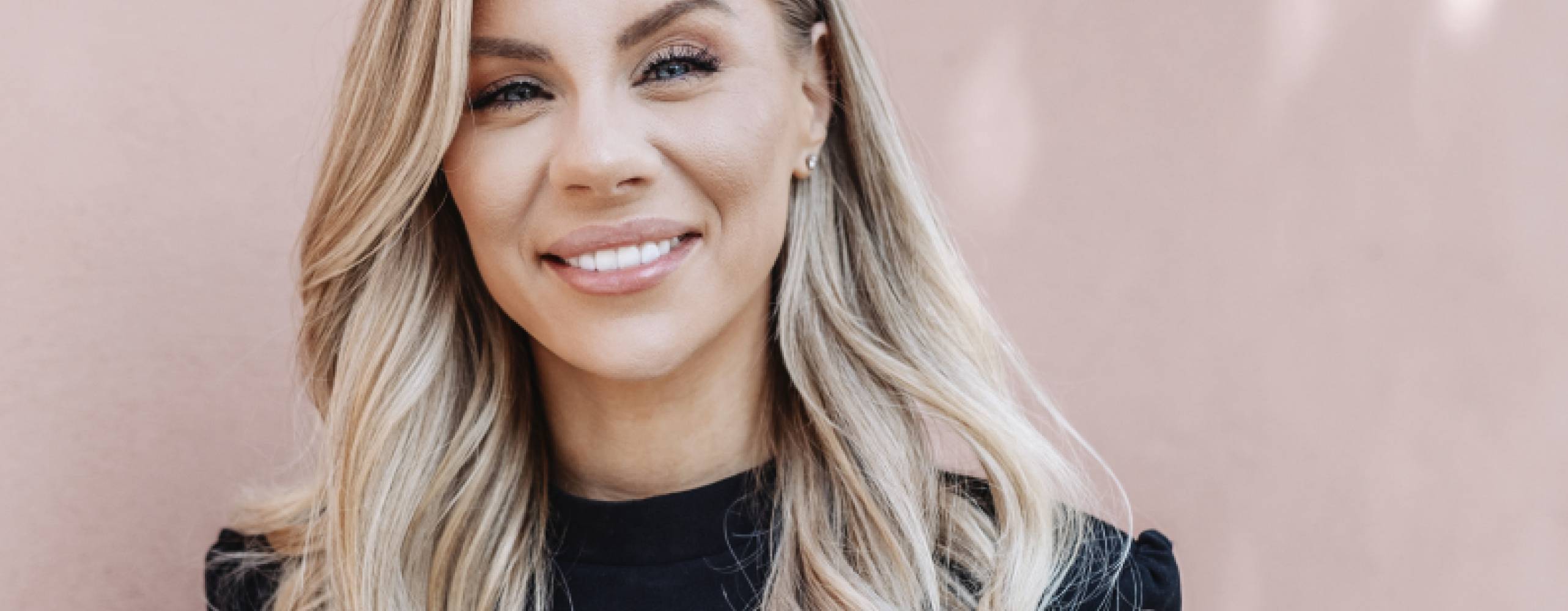 Therése Lindgren leendes framför beige vägg med solkatter