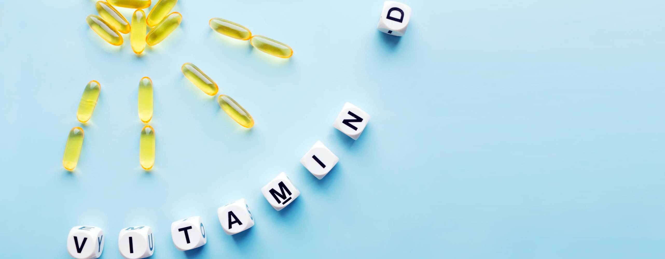 D vitaminpiller formade som en sol och tärningar med texten vitamin D mot en ljusbjå bakgrund