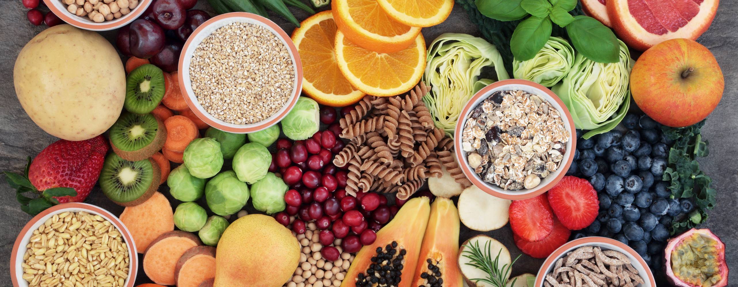 Hälsomat koncept för en högfiberdiet med frukt, grönsaker, spannmål, fullkornspasta, korn, baljväxter och örter.